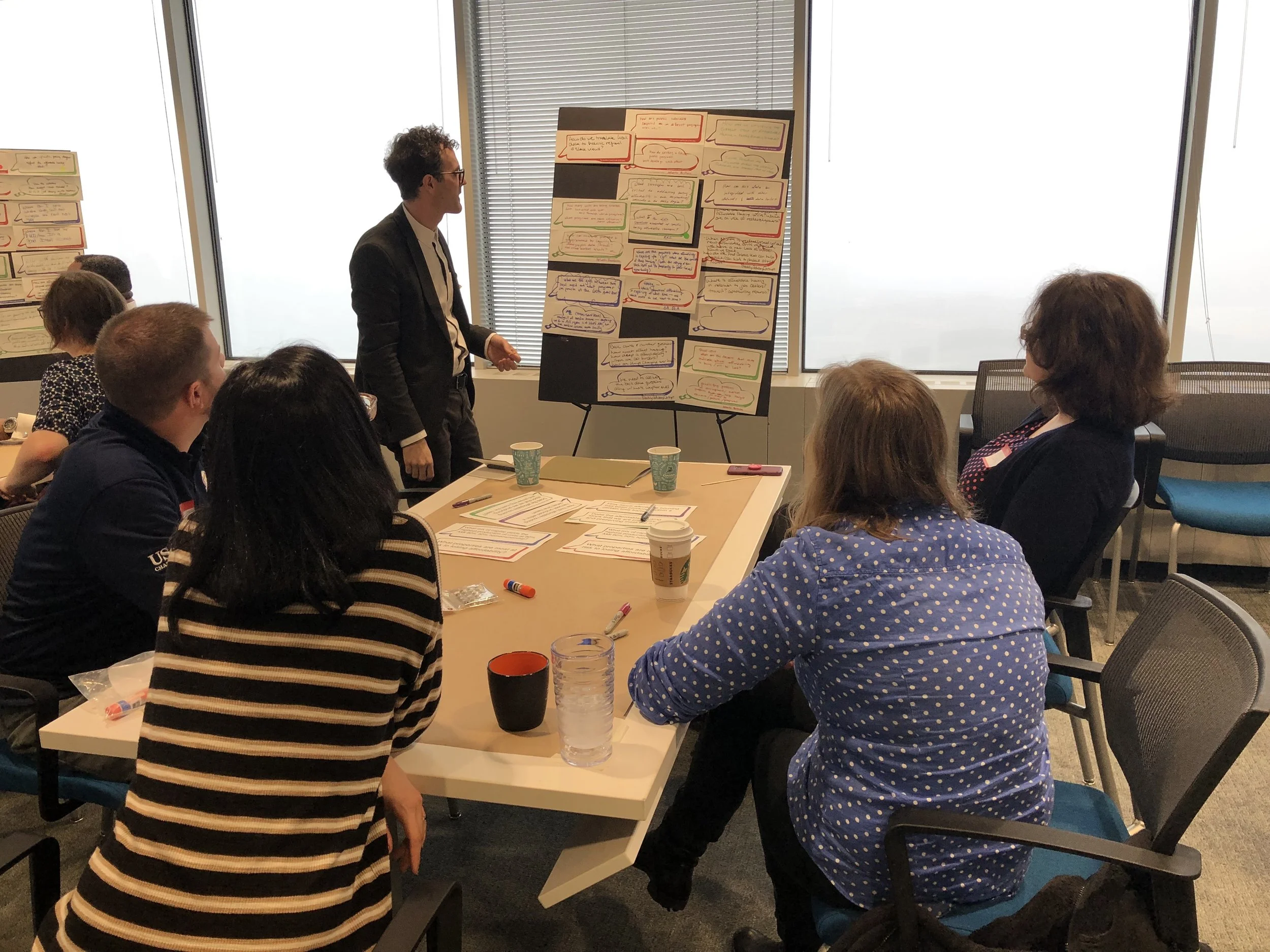 A workshop participant stands up with his group to go over the questions so that others can vote.