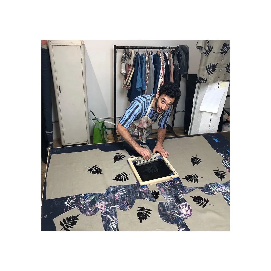 Tony stands over sections of the shirt, hand screen printing each fern leaf on the shirt one by one to show the process of how the shirt was made