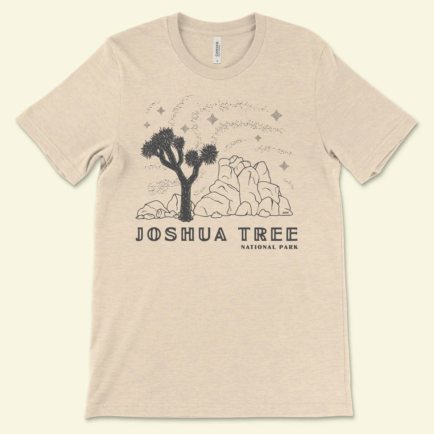 A shirt featuring an illustration of Joshua Tree National Park, with a joshua tree in front of large rock formations and a starry background. It is reminiscent of 1 color designs of postcards from the past