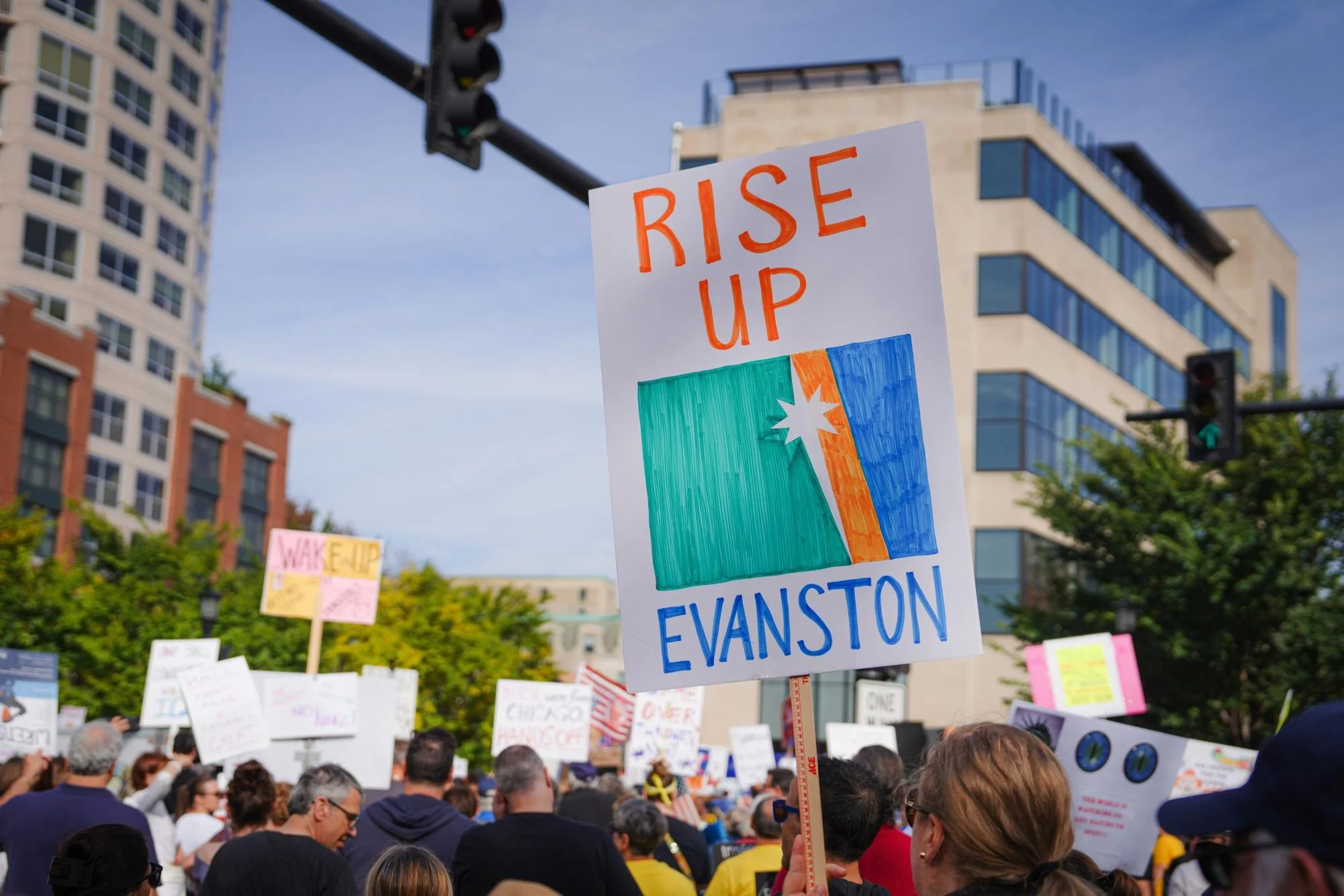 A protester holds up a sign that says “Rise Up Evanston” during the “No Kings” protest at Evanston’s Fountain Square Saturday morning.