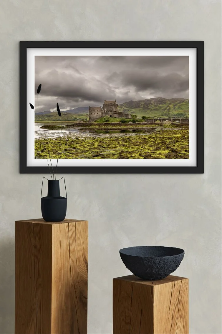 Framed Eilean Donan Castle Scottish Highlands landscape photograph displayed above wooden plinths on a textured wall