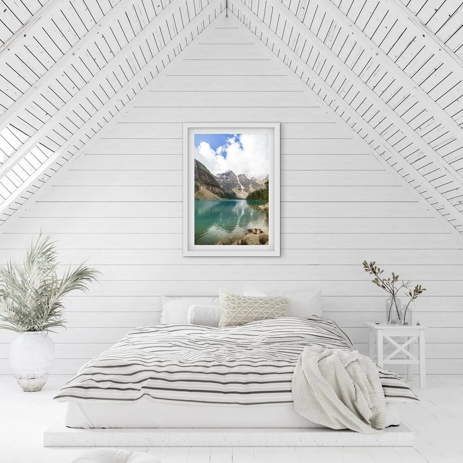 Framed Moraine Lake Banff National Park wall art print displayed above a bed in a bright minimalist bedroom