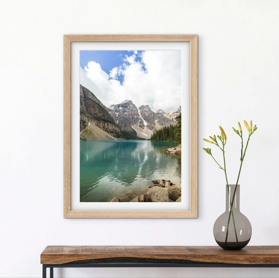 Framed Moraine Lake Canadian Rockies landscape photograph displayed above a wooden console table