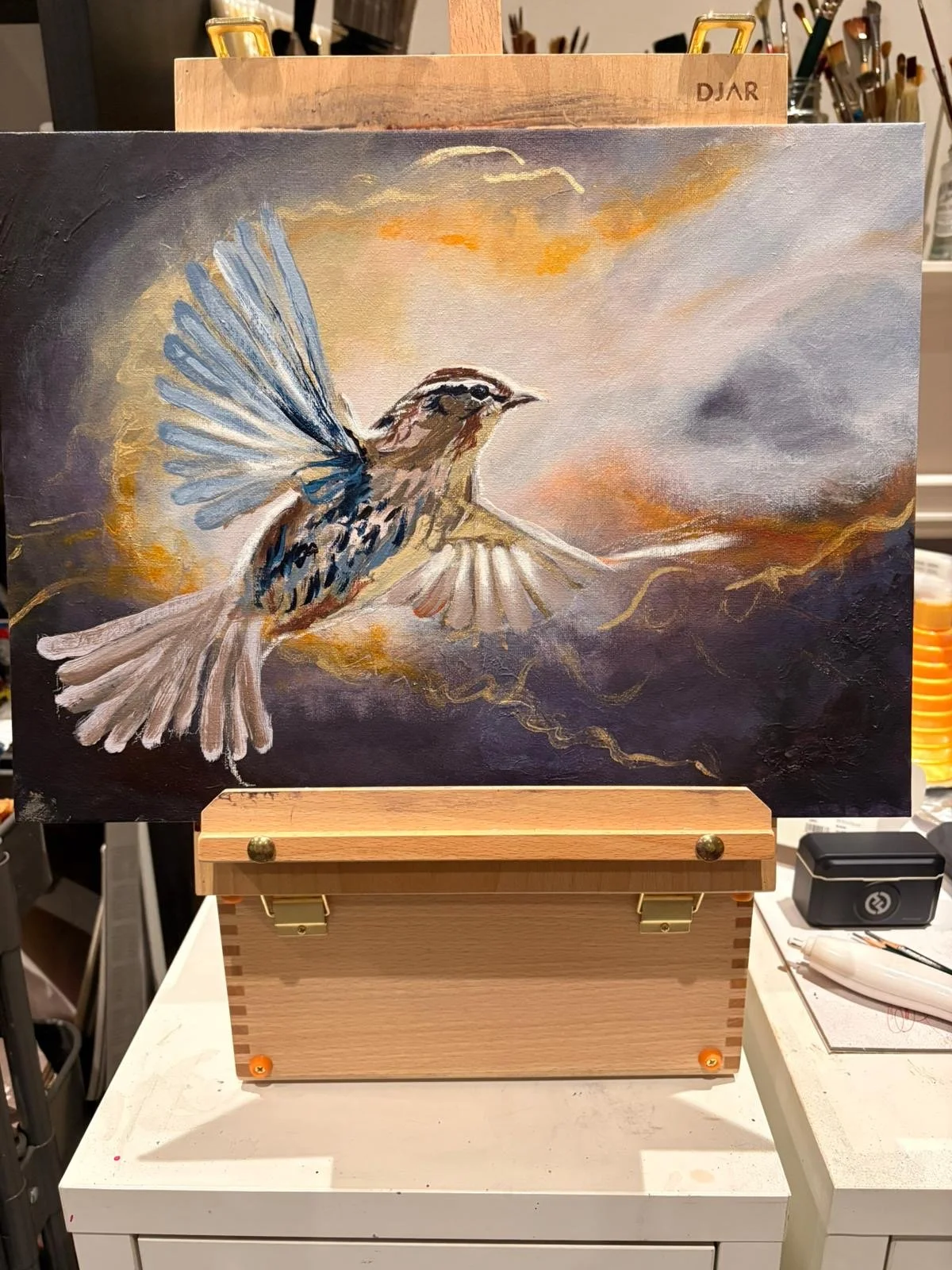 A painting of a bird in flight against a colorful sky with clouds and warm tones.