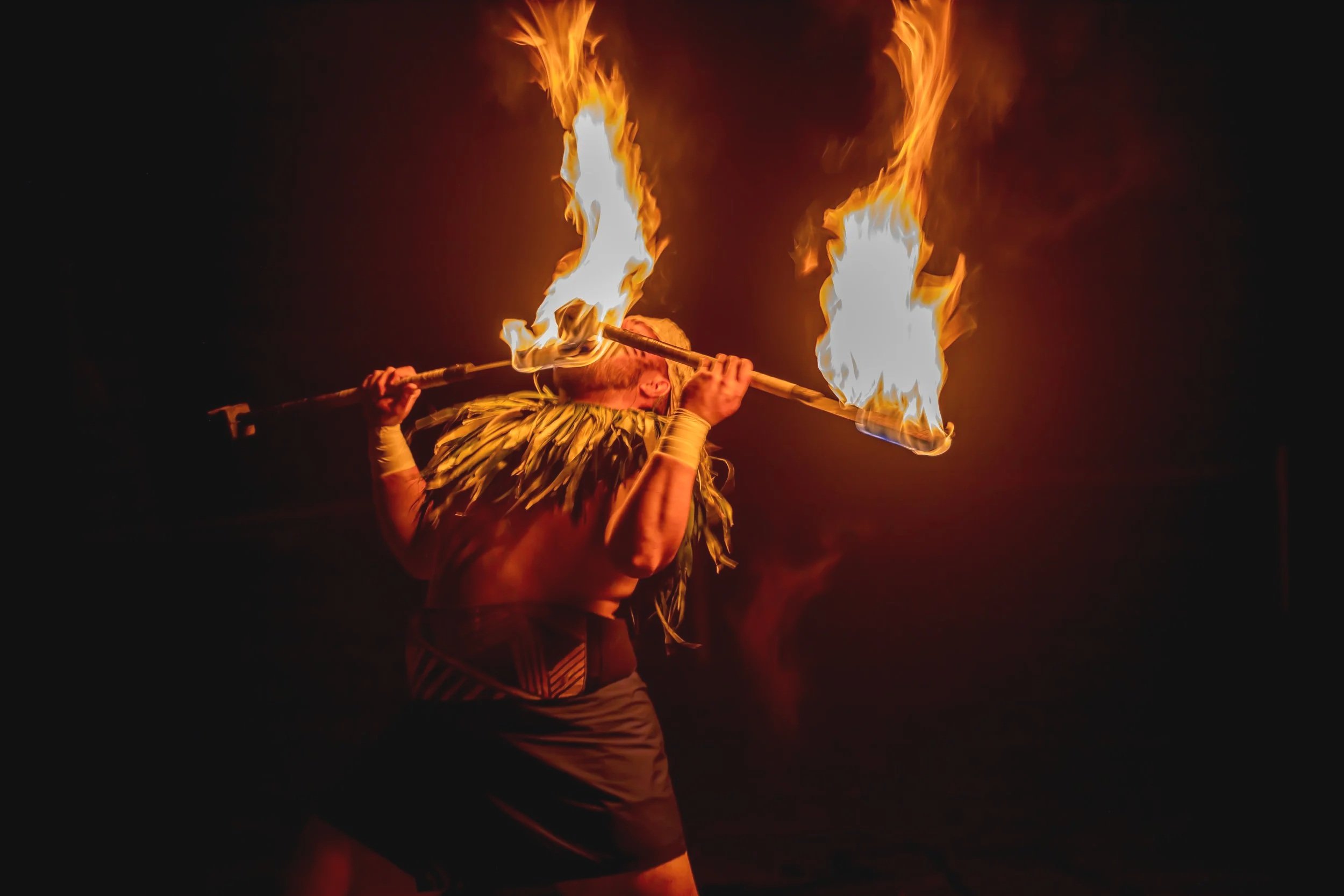 A Polynesian fire knife dancer performs with flaming sticks during a traditional lūʻau at Waimea Valley in North Shore Oʻahu, Hawaii.