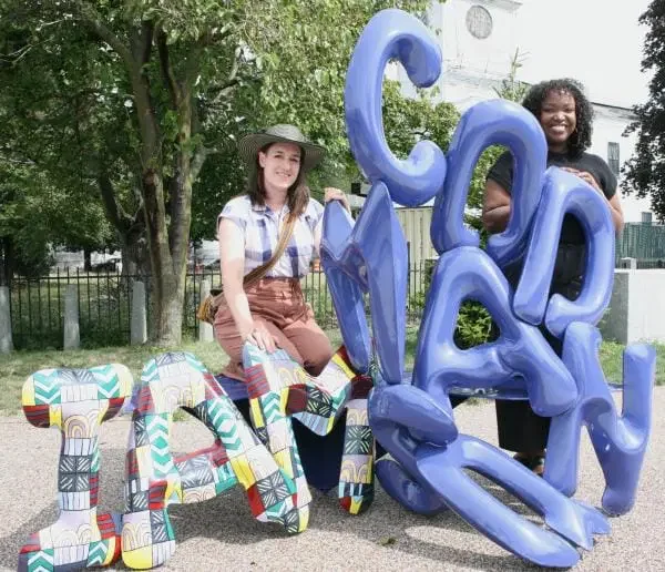 Destiny Palmer and Alaina Mahoney stand behind Destiny's "I AM CODMAN SQUARE" sculpture.