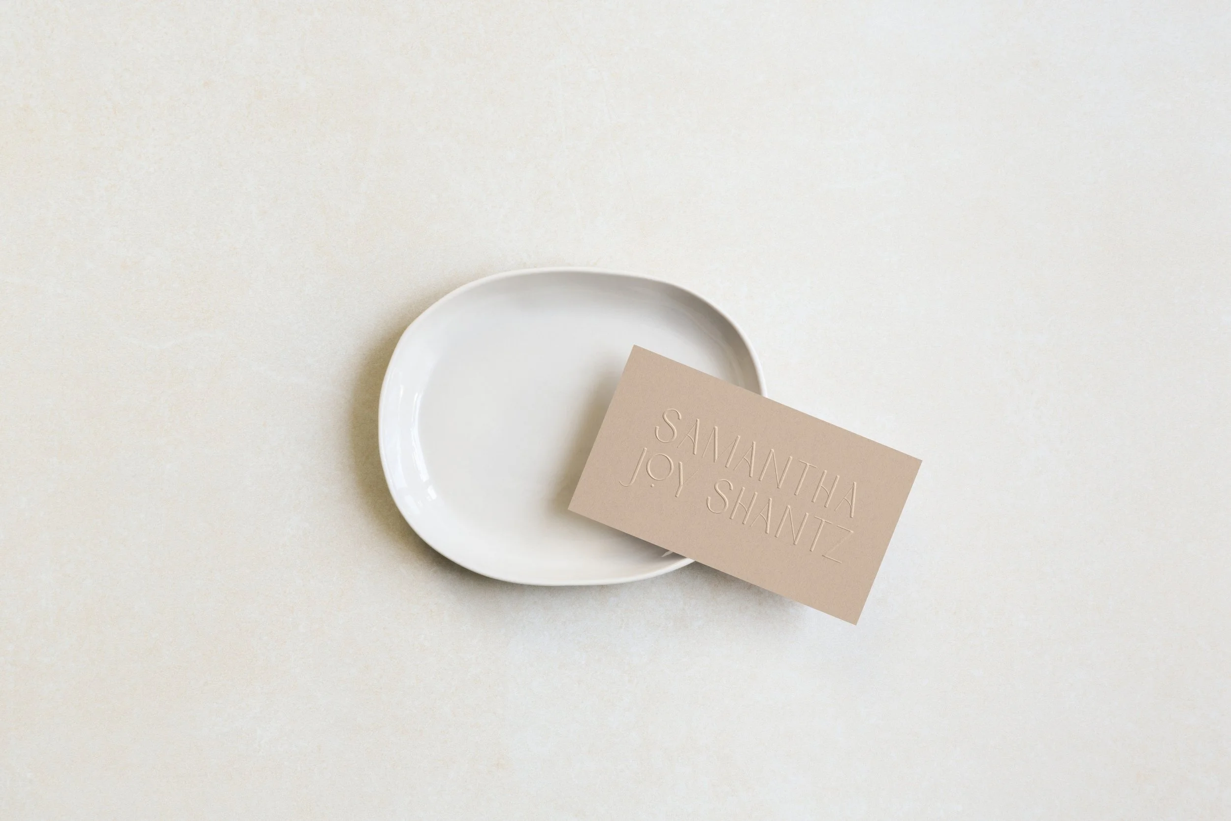 White ceramic plate with beige business card on light background