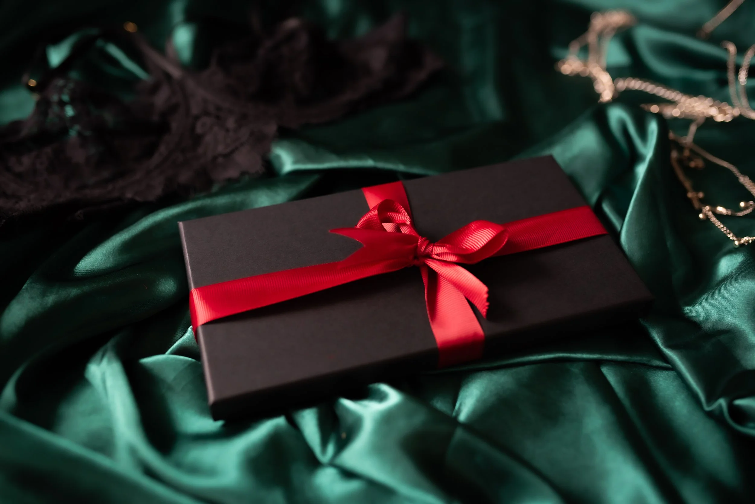 Boudoir photography gift voucher in a black box with red ribbon on emerald satin, Marieke Captures Glasgow