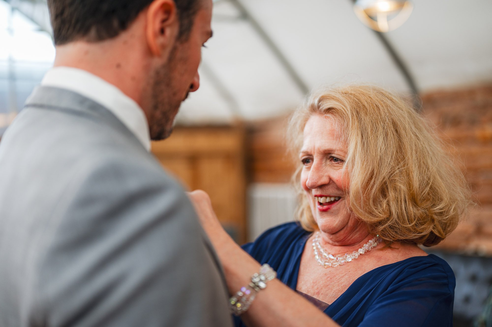 mother of groom putting on boutonniere