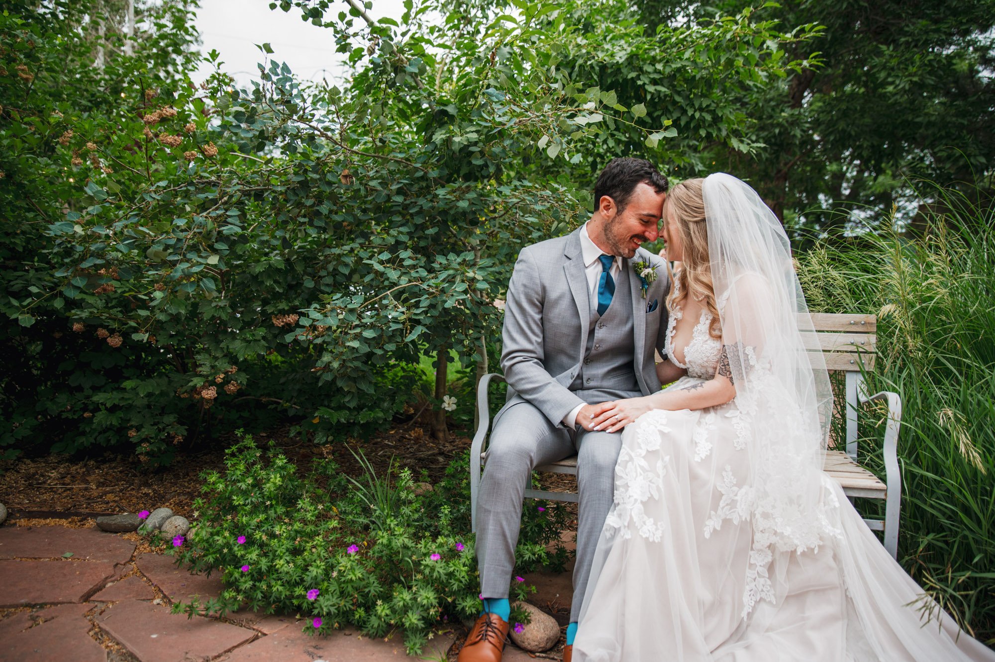 bride and groom sitting on a bench with their foreheads touching