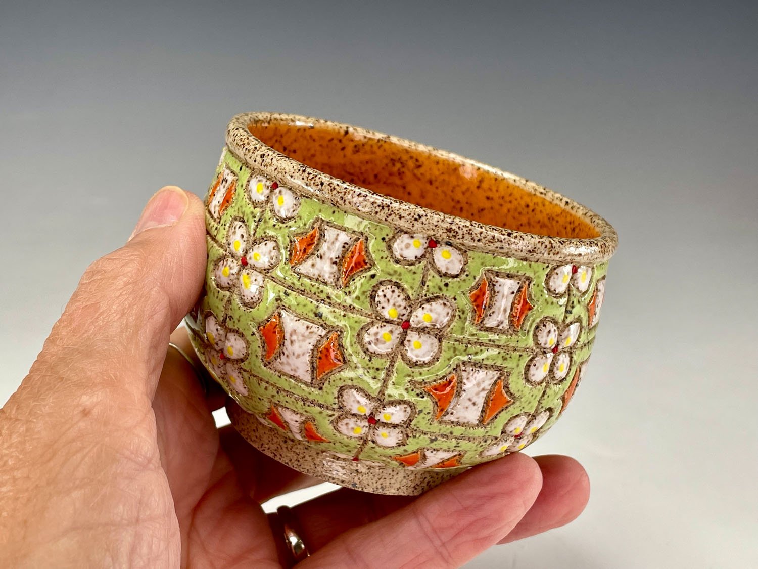 Hand holding Citrus stoneware tea bowl stoneware cup