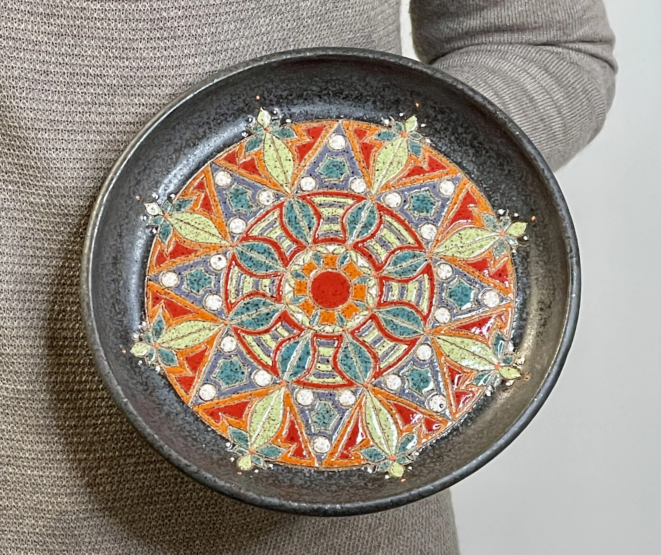 Hand holding Colorful carved small stoneware plate