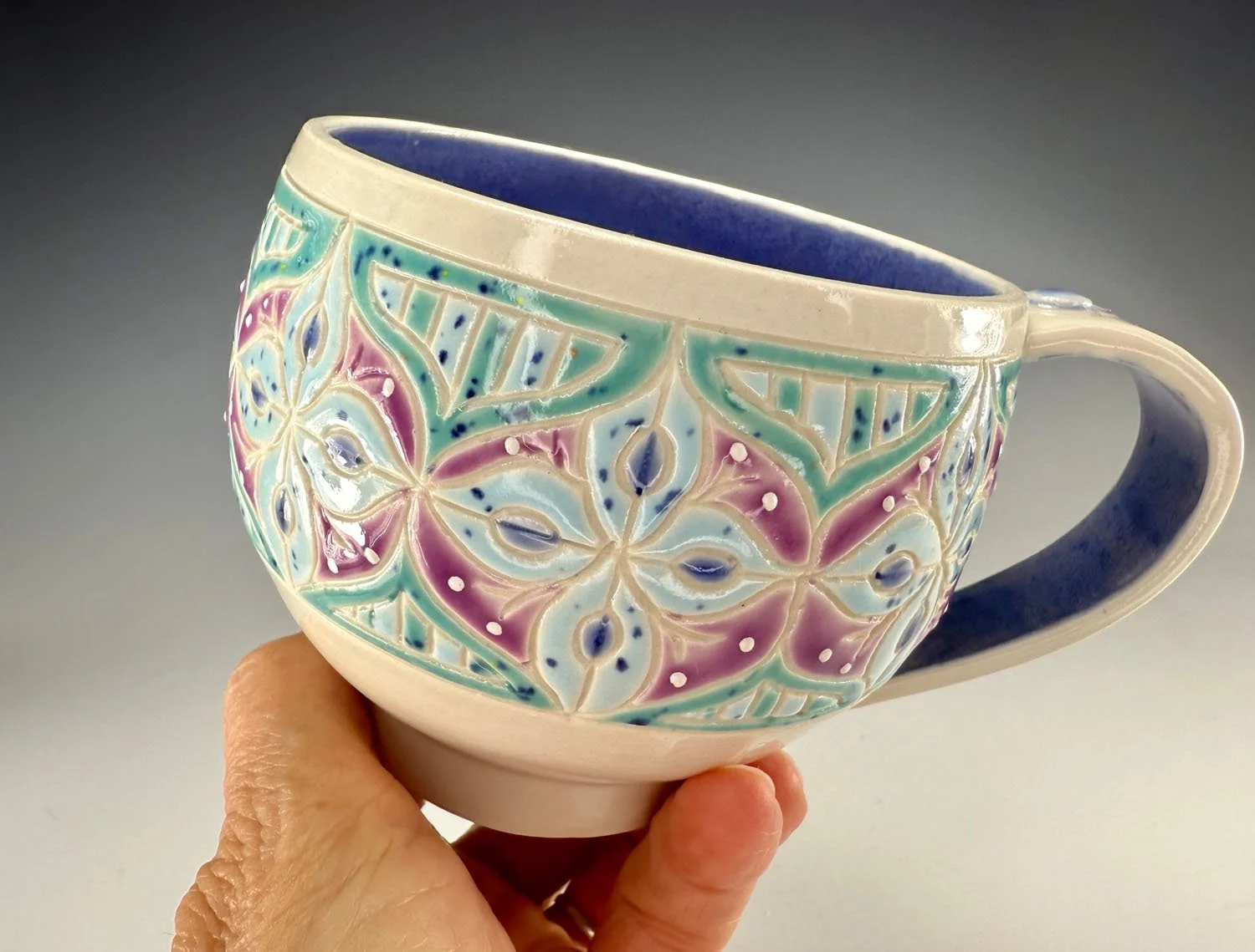 Hand holding Blue grape carved porcelain mug
