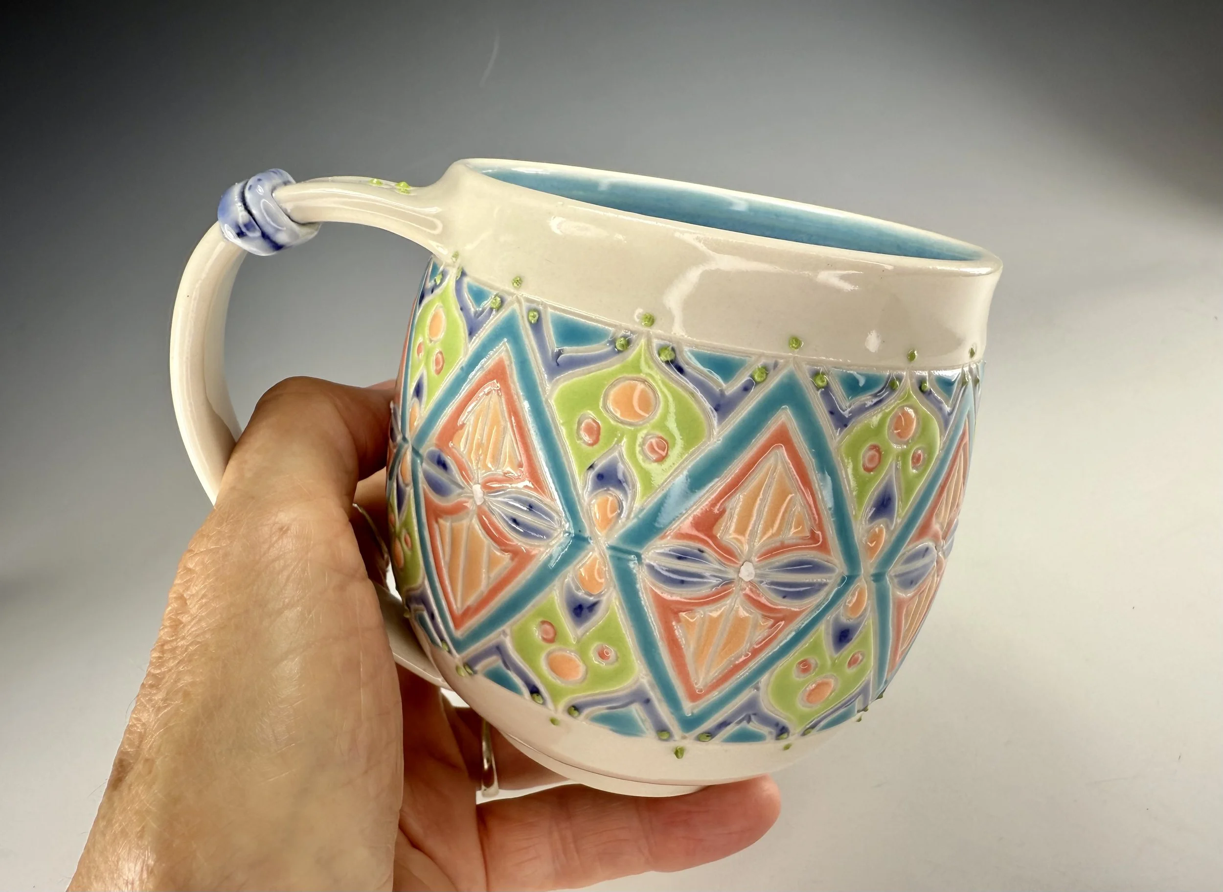 Hand holding Candy colored carved porcelain mug