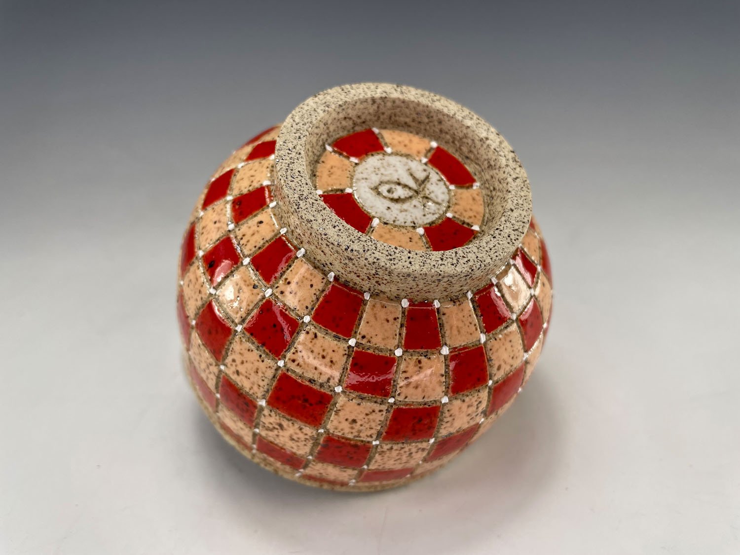 Side and bottom view of Peach red checkerboard stoneware tea bowl