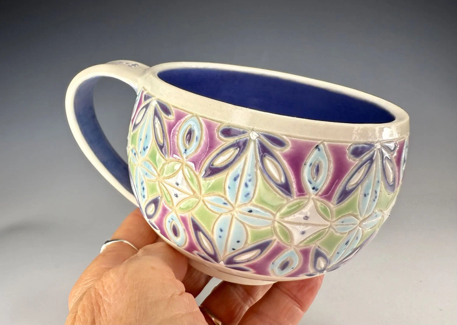 Hand holding Purple blue carved porcelain mug