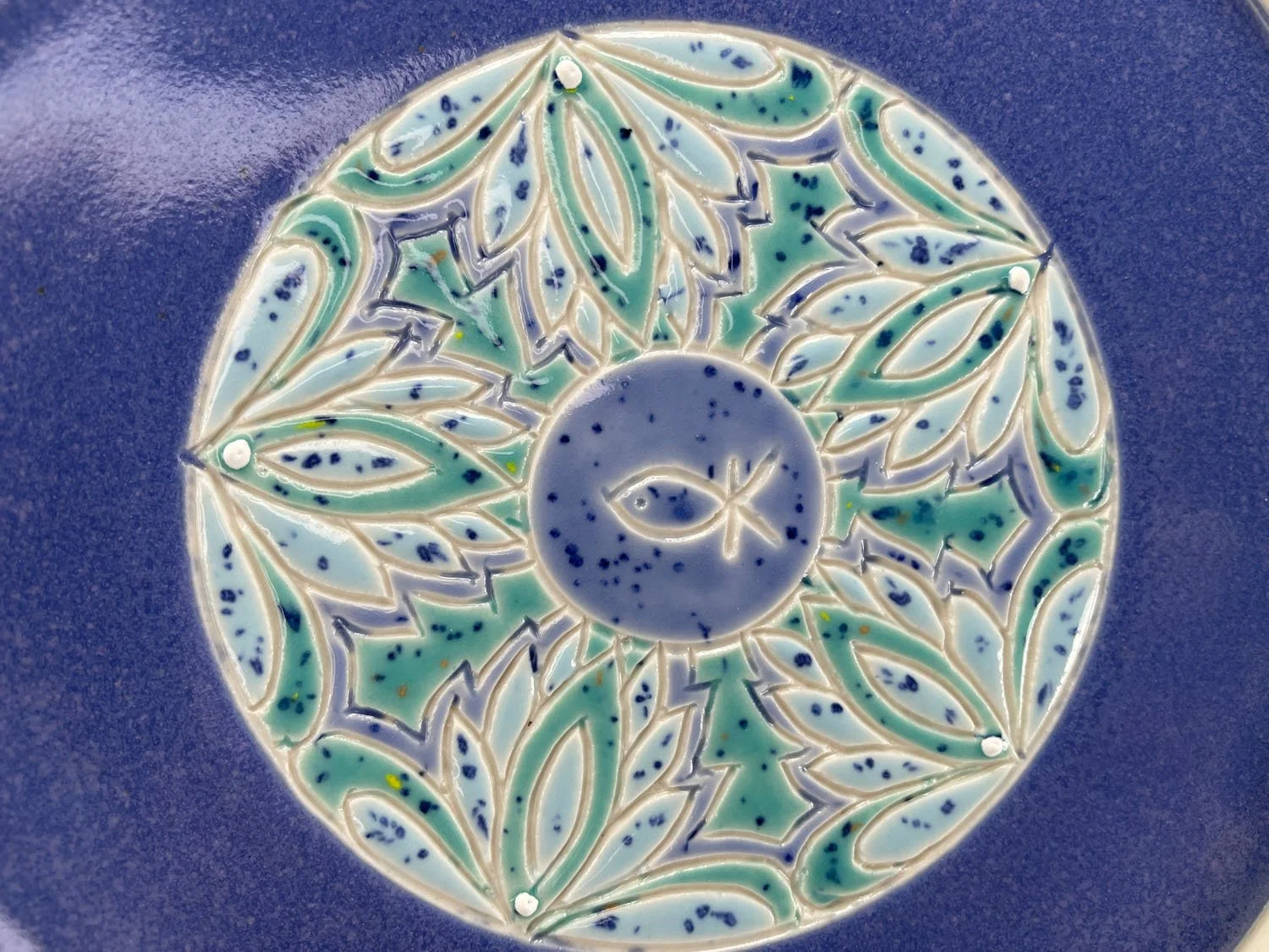 Closeup of back design on Porcelain plate with green blue border and periwinkle blue base