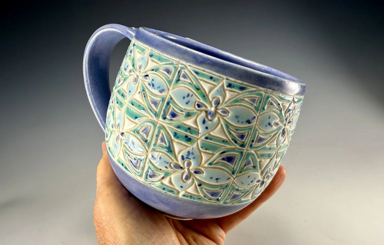 Hand holding Misty blue carved porcelain mug