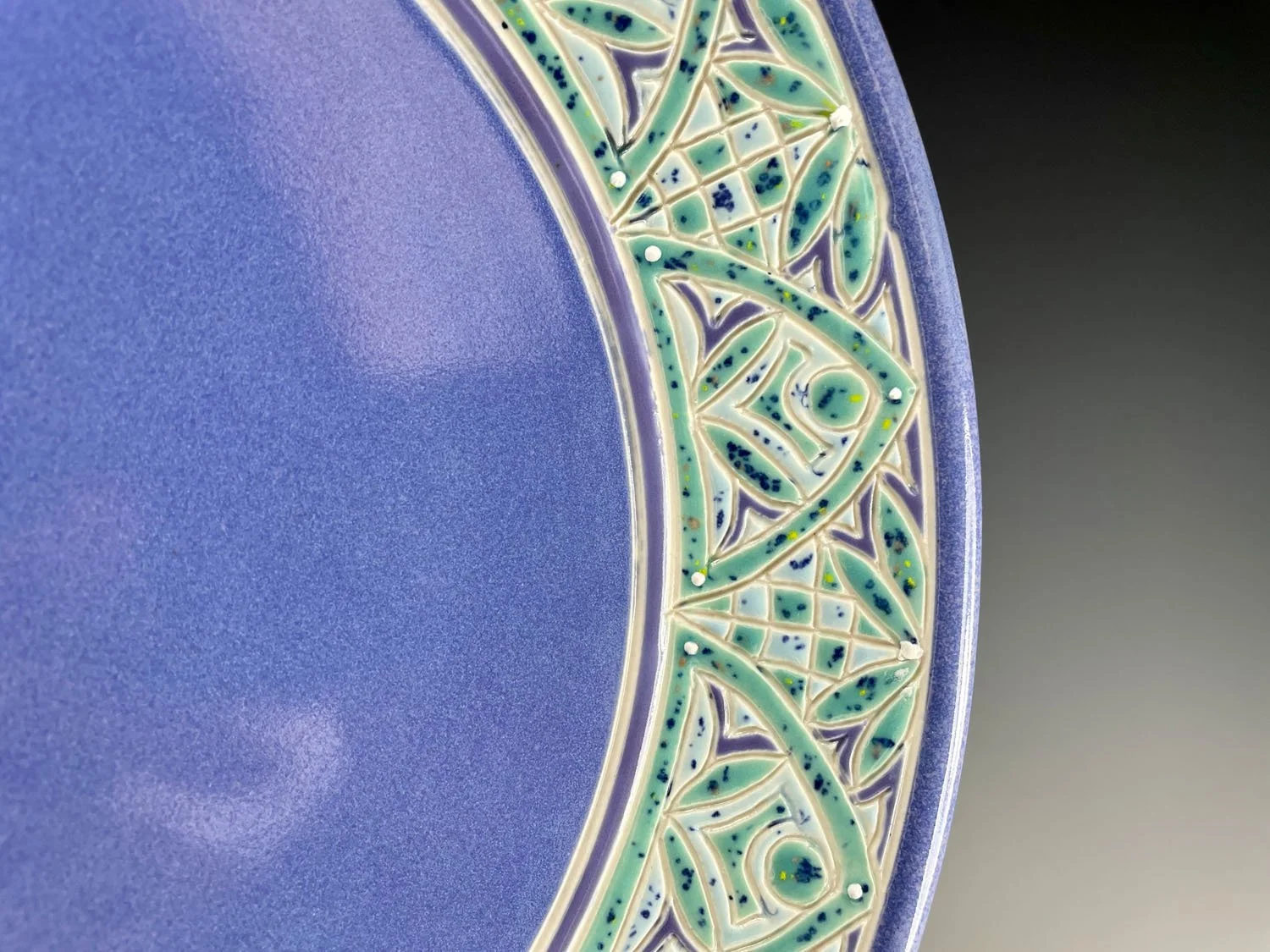 Rim closeup of Hand carved blue porcelain platter plate with blue green design