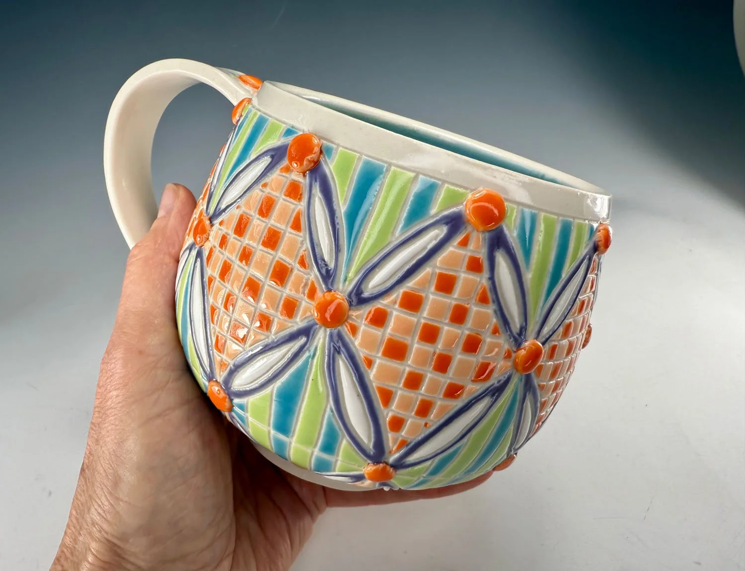 Hand holding Carved checkered porcelain mug