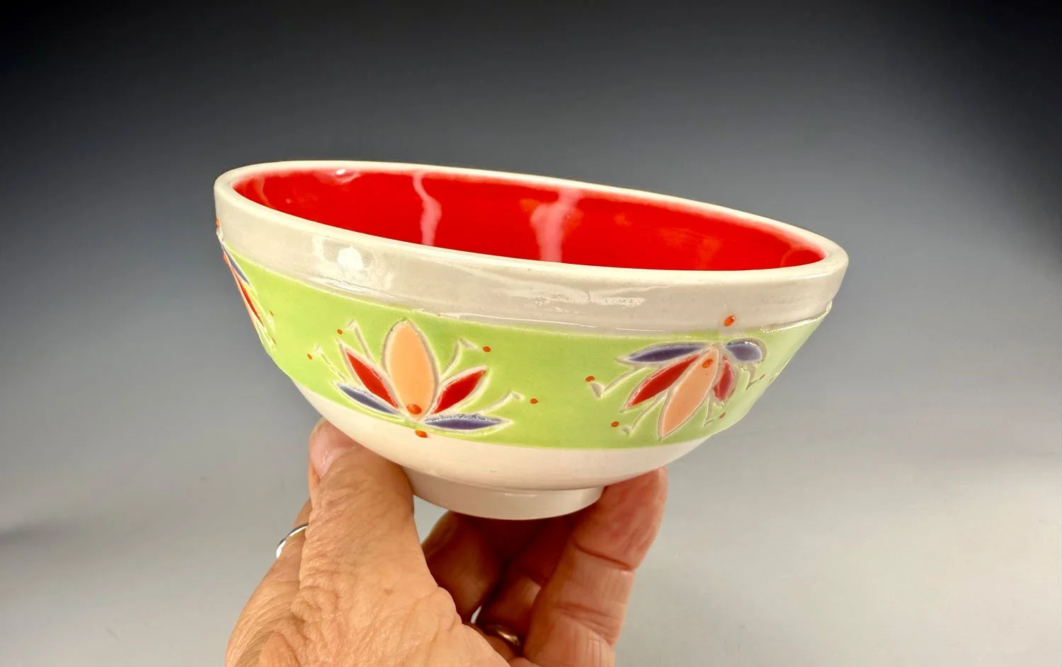 Hand holding bowl 2 of Bowl 1 of Porcelain 2 bowl snack set w red liner and carved outer designs