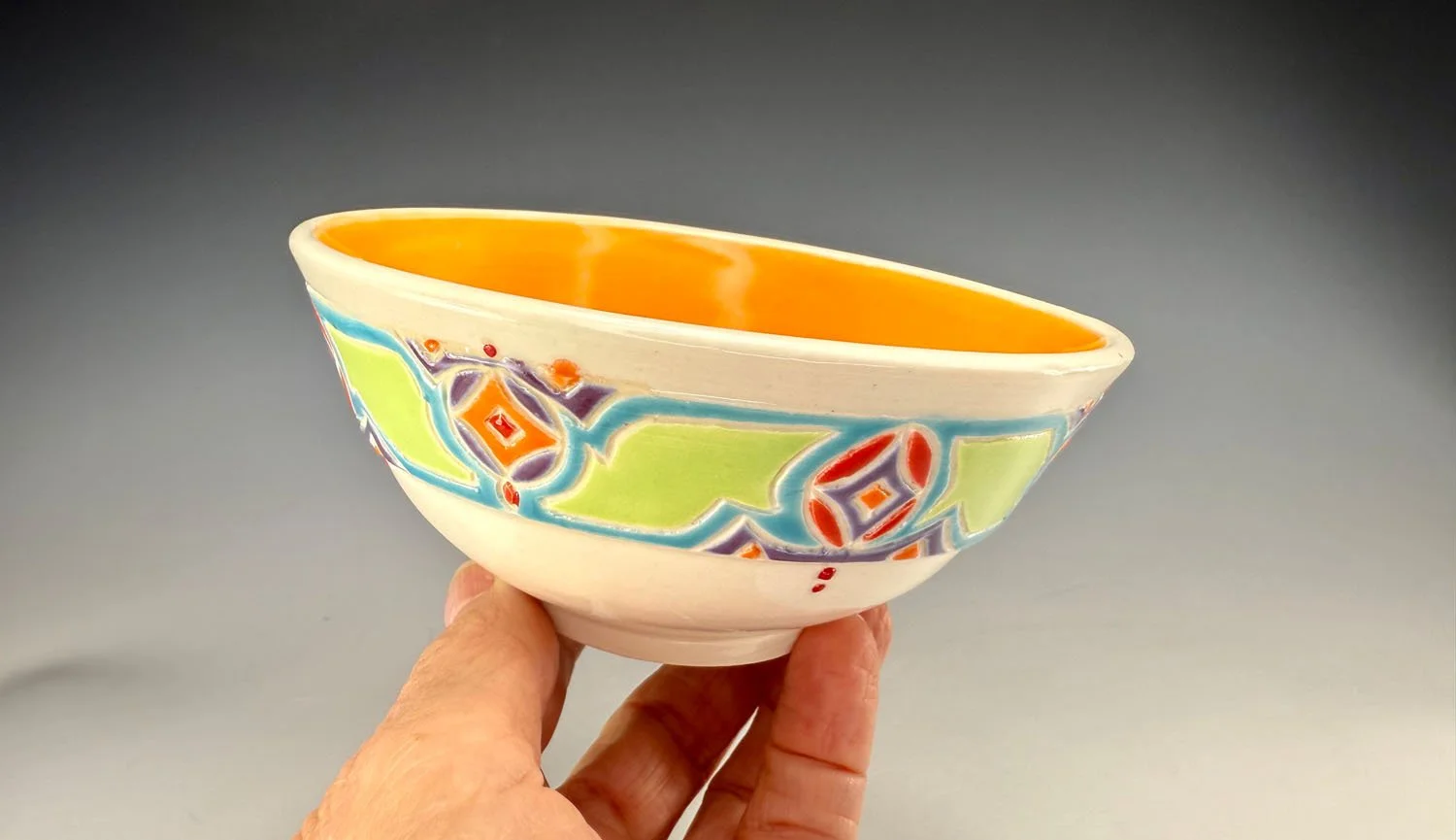 Hand holding bowl 1 Tangerine lined porcelain two bowl snack set with carved outer bands
