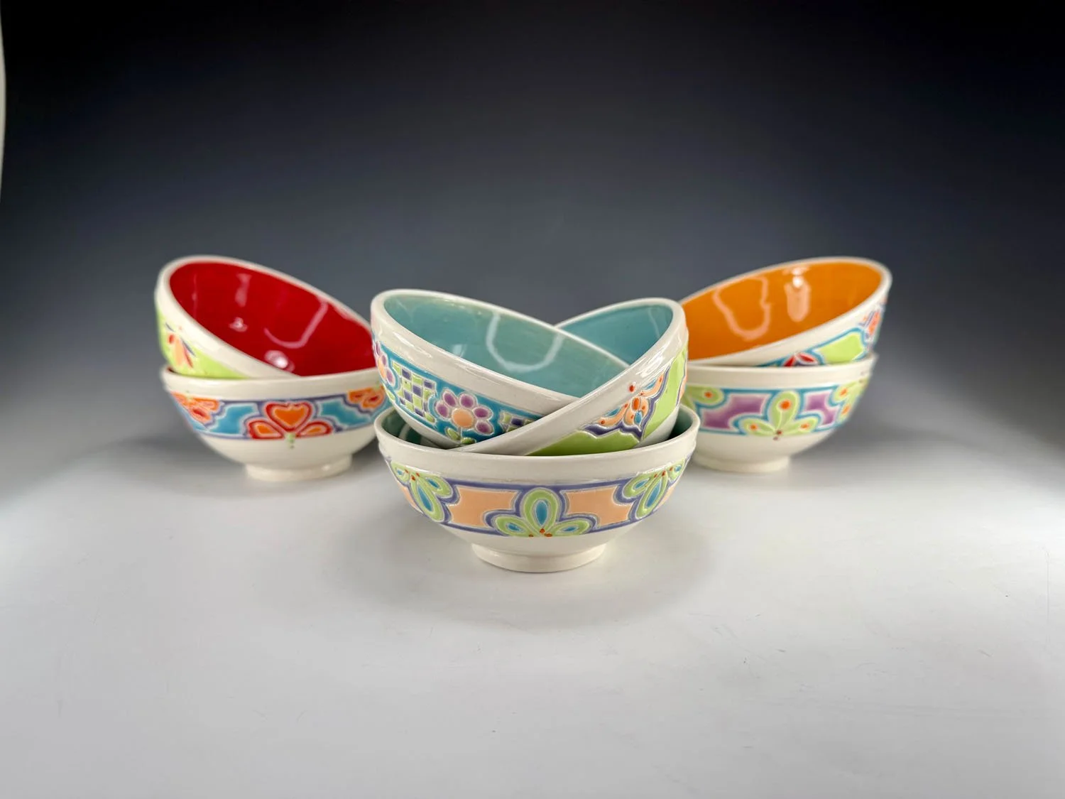 Seven carved porcelain snack bowls with colored liners and carved exteriors