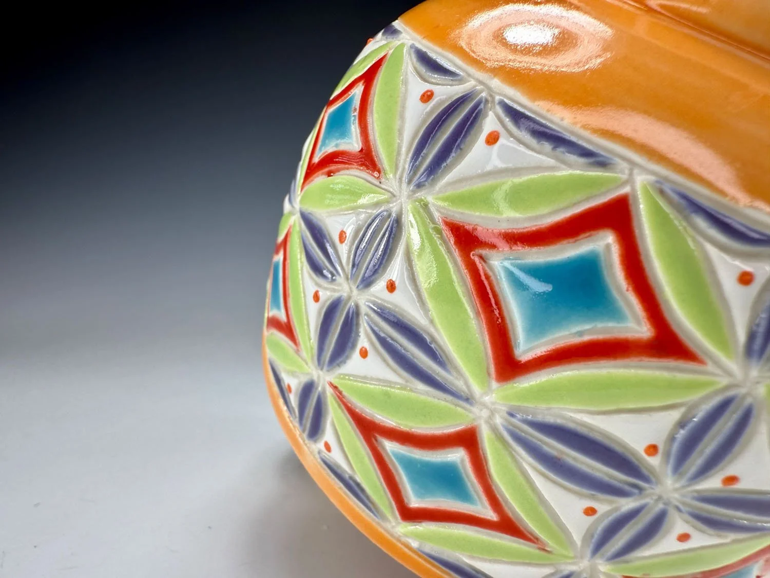 Closeup of carved design on Orange carved porcelain mug