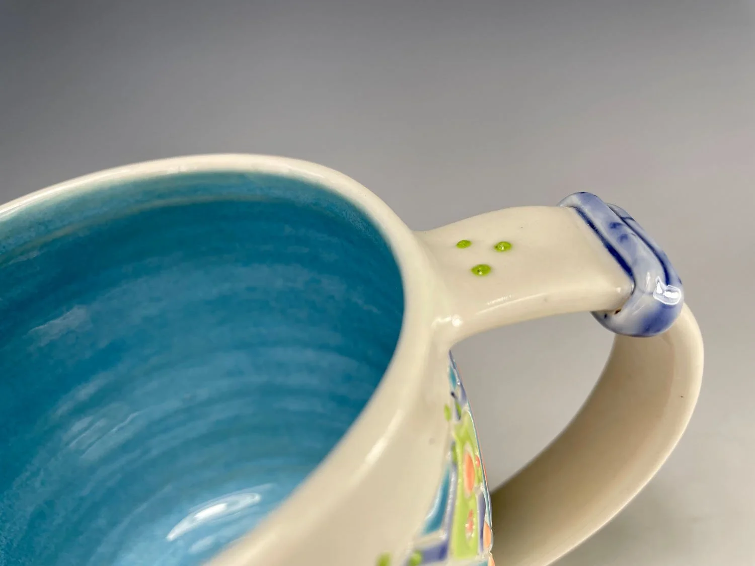 Handle closeup on Candy colored carved porcelain mug