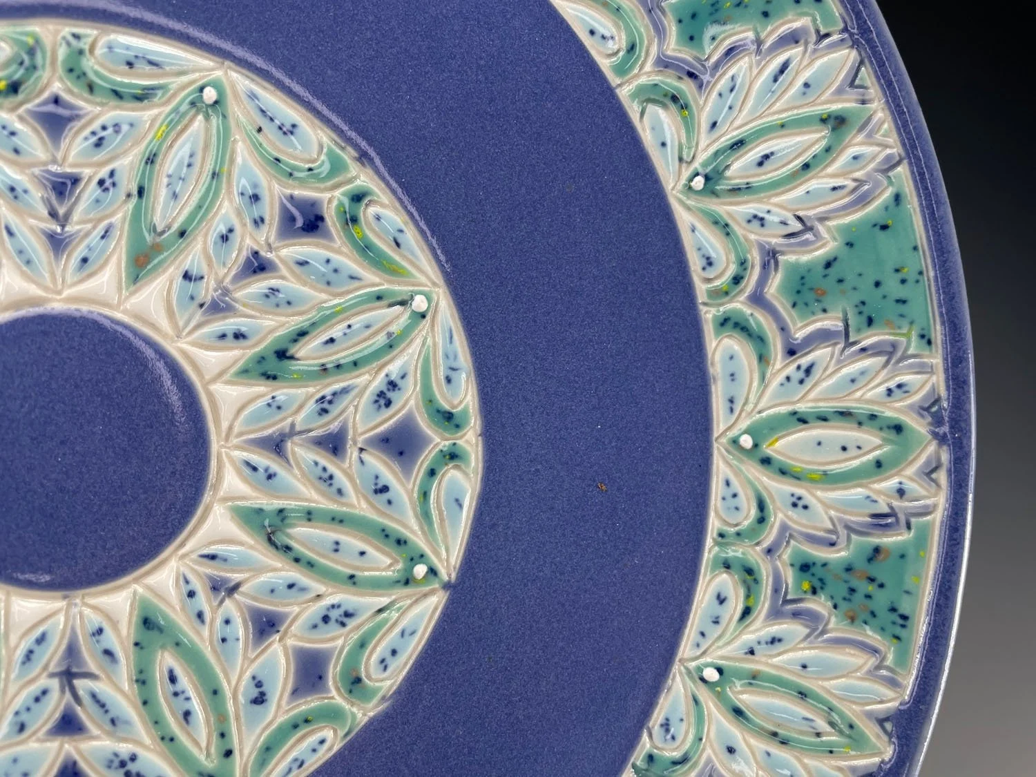 Closeup rim design on Porcelain plate with green blue border and periwinkle blue base