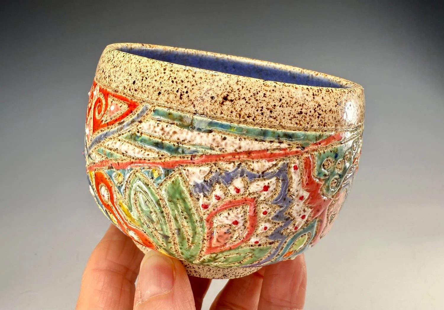 Hand holding Freeform carved stoneware tea bowl