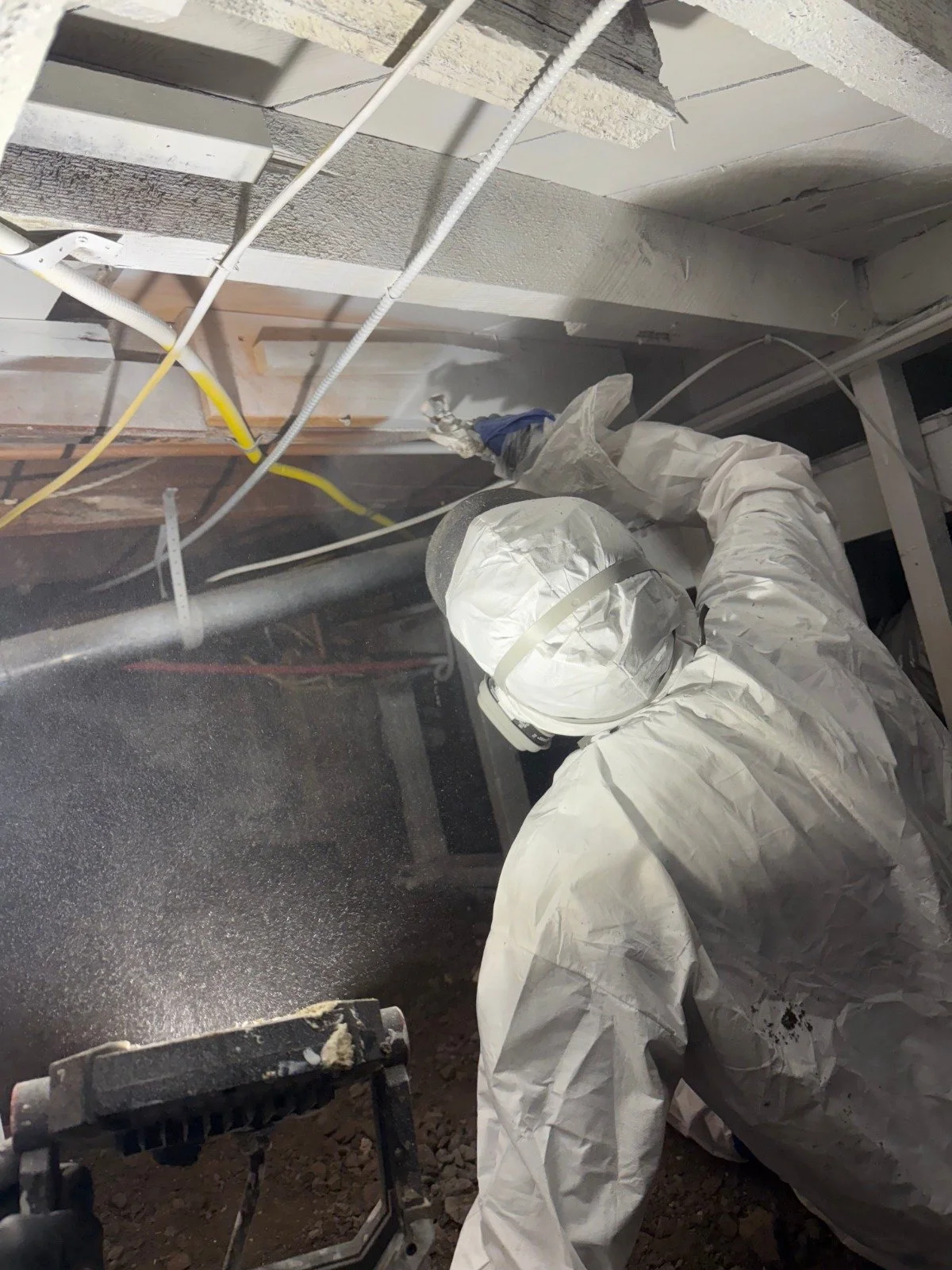 Researcher in full protective gear using a fogger to sanitize a surface.