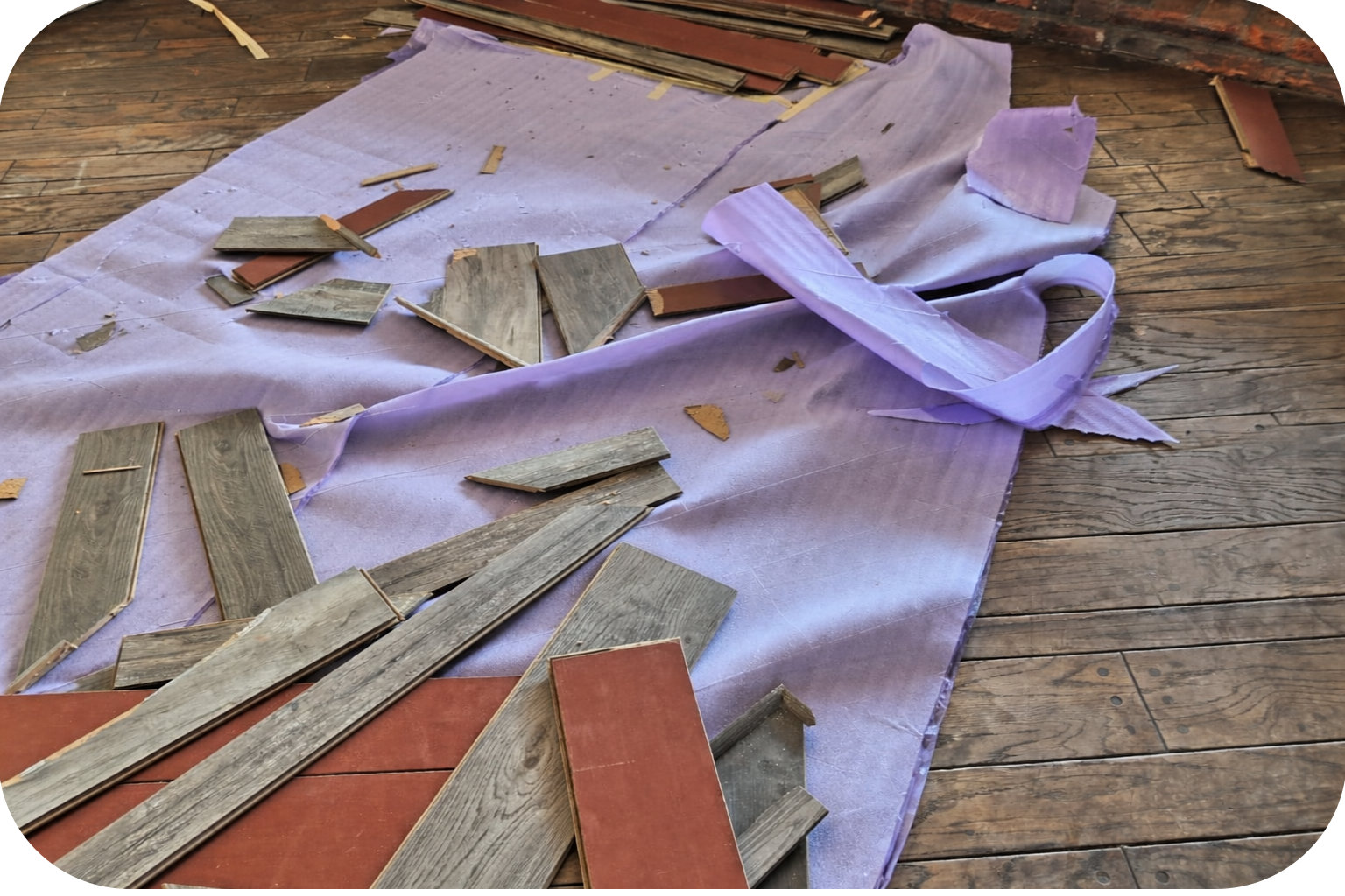 A construction worker operating a lift on the side of an orange building with black windows.
