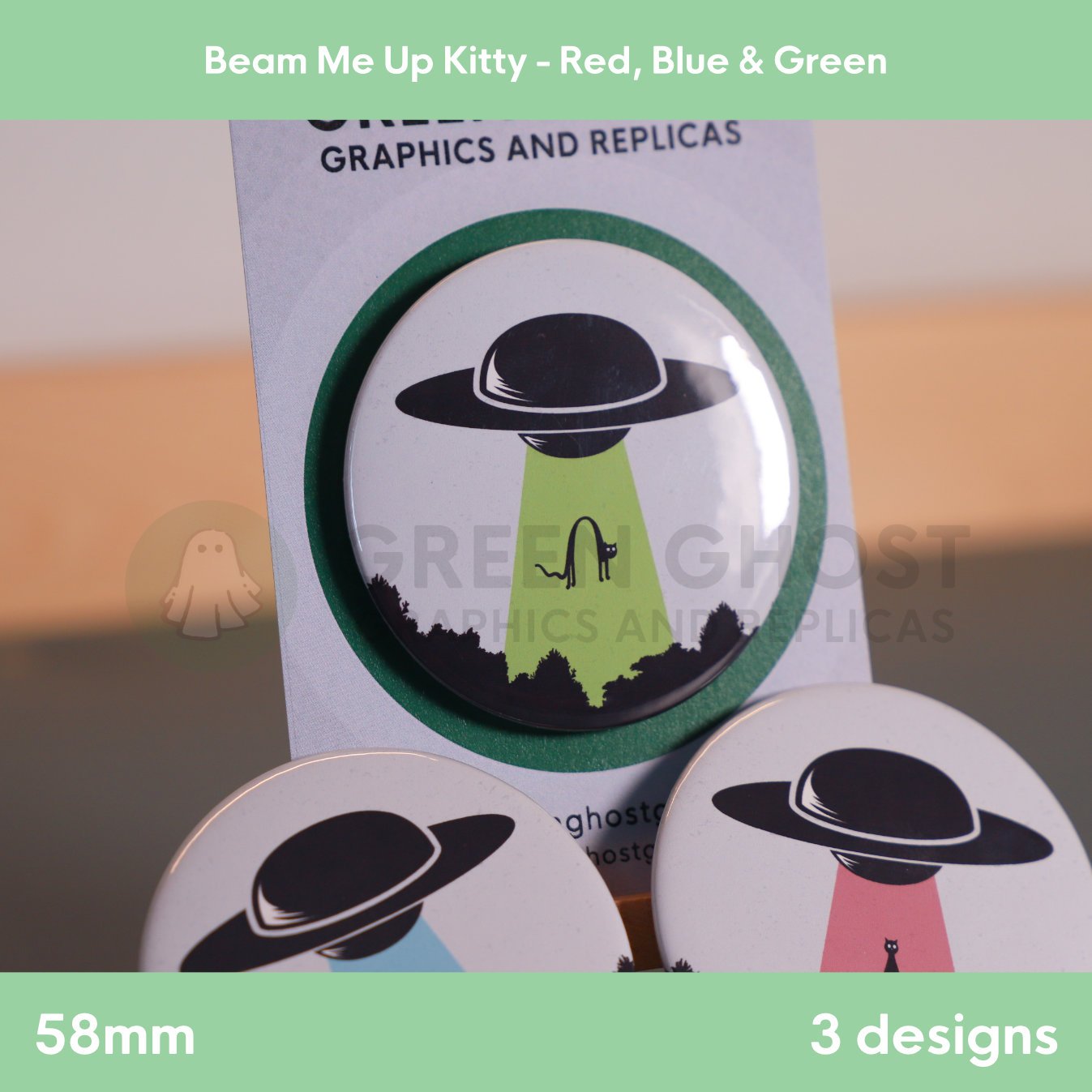 Three round badges with coloured UFO beams lifting a cat displayed on a branded backing card.