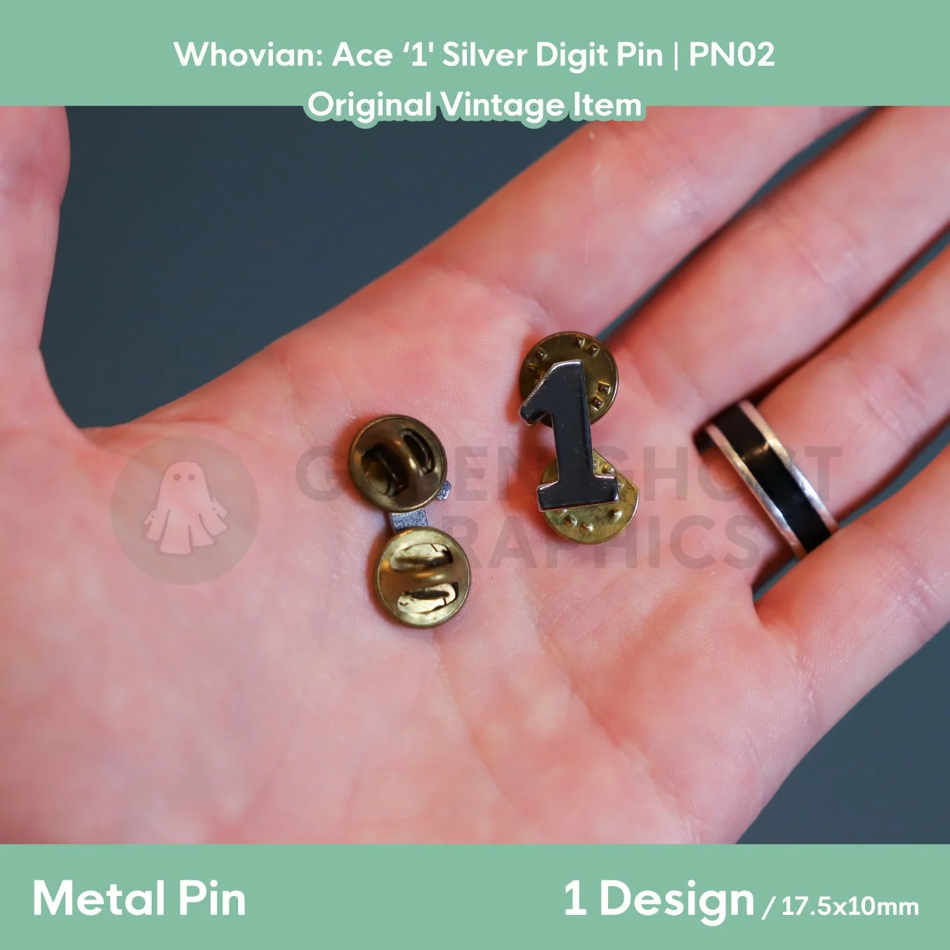 A silver digit “1” pin shown in a hand alongside two brass‑coloured clutch backs and rear fastening fittings.