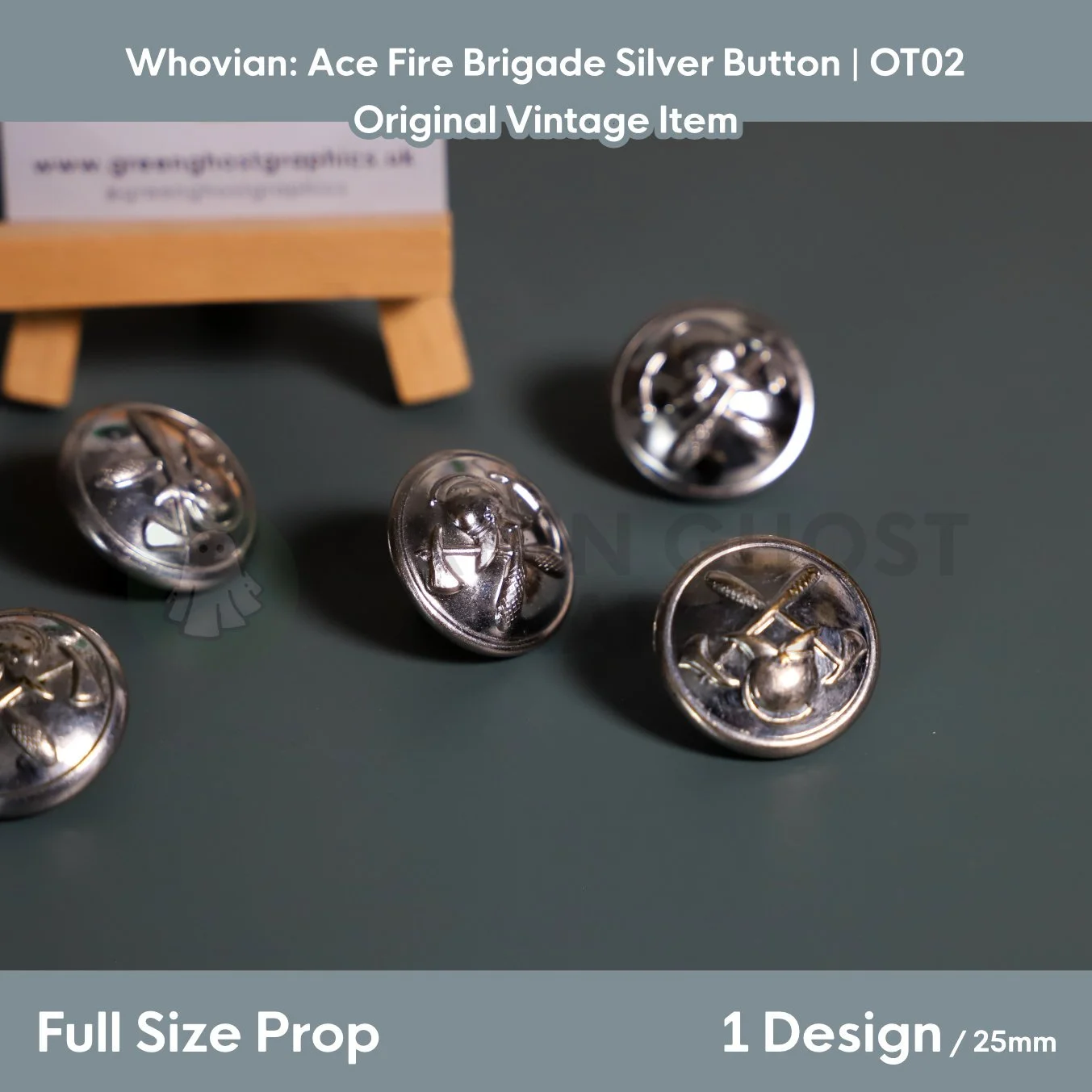 Multiple shiny silver fire brigade buttons with embossed firefighting emblems positioned in front of a branded card on a tabletop display.