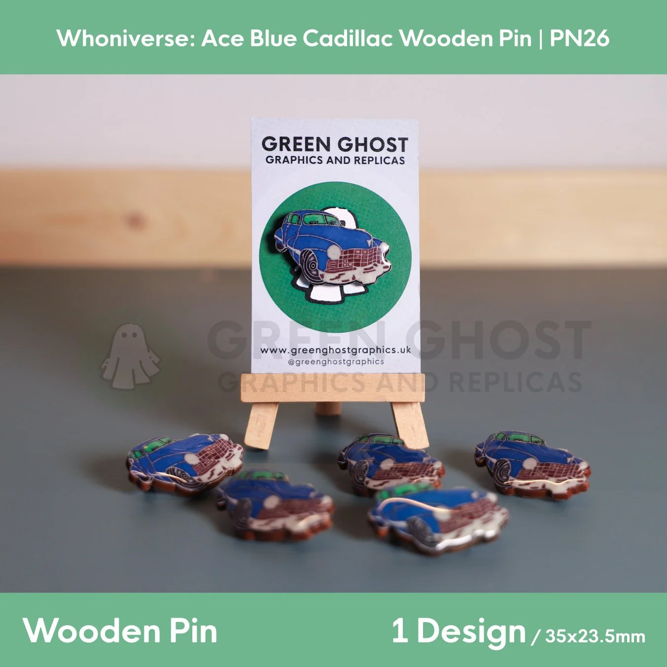 A wooden pin shaped like a blue Cadillac car attached to a branded backing card on a wooden easel, with several identical pins arranged on the surface in front.