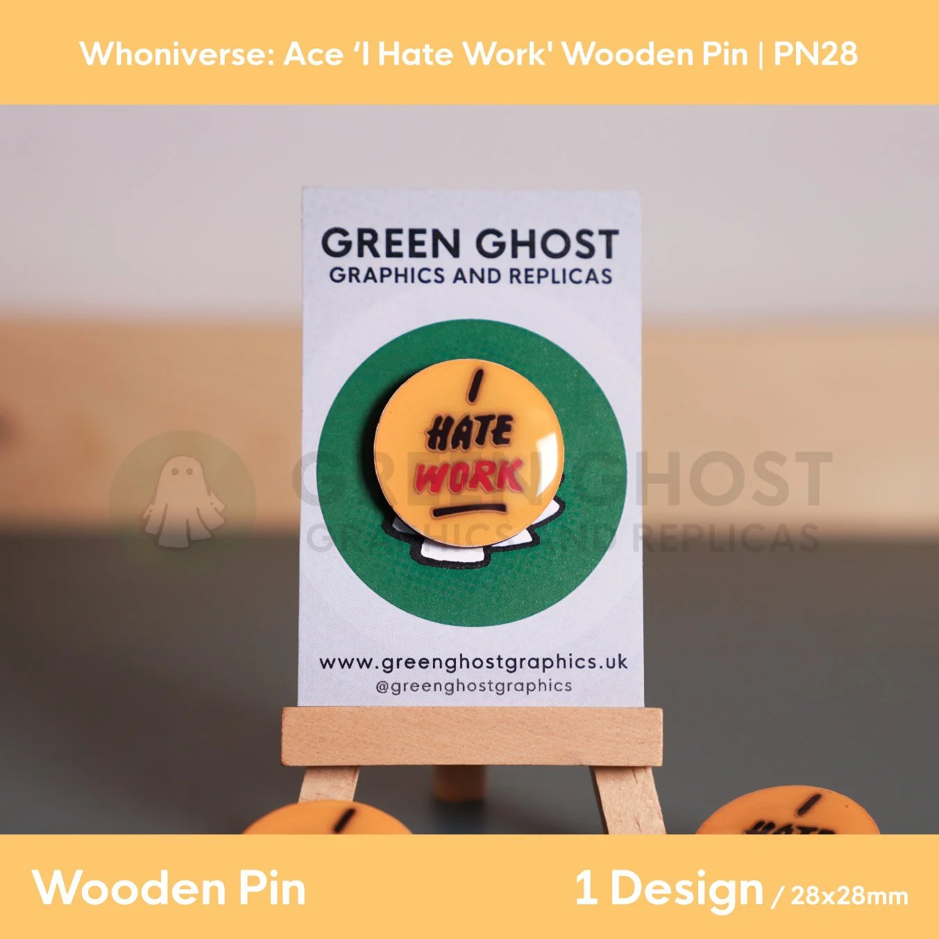 A yellow circular “I HATE WORK” wooden pin mounted on a branded backing card on a wooden easel, with additional pins partially visible at the bottom of the frame.