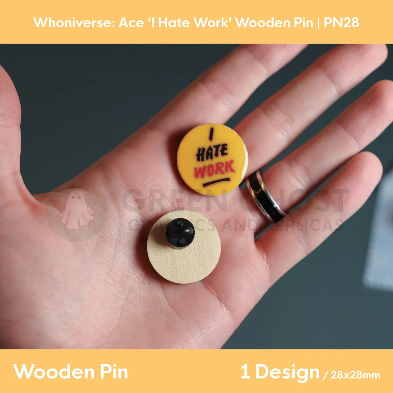 A close‑up of two circular “I HATE WORK” wooden pins held in a hand, showing the front text design and the back with a clasp attachment.