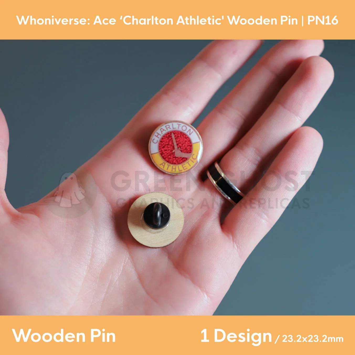 A close‑up of two circular wooden “Charlton Athletic” pins held in a hand, showing the front design with the sword emblem and the back with a rubber clasp.