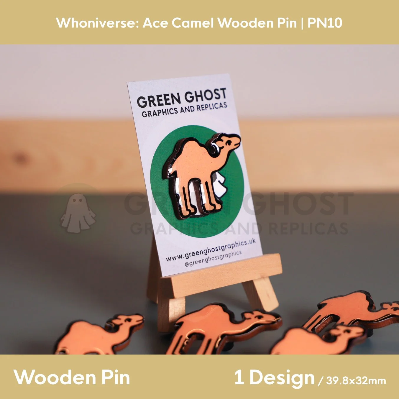 A wooden camel‑shaped pin attached to a branded backing card featuring a green circular background, displayed on a wooden easel with additional pins scattered around it.