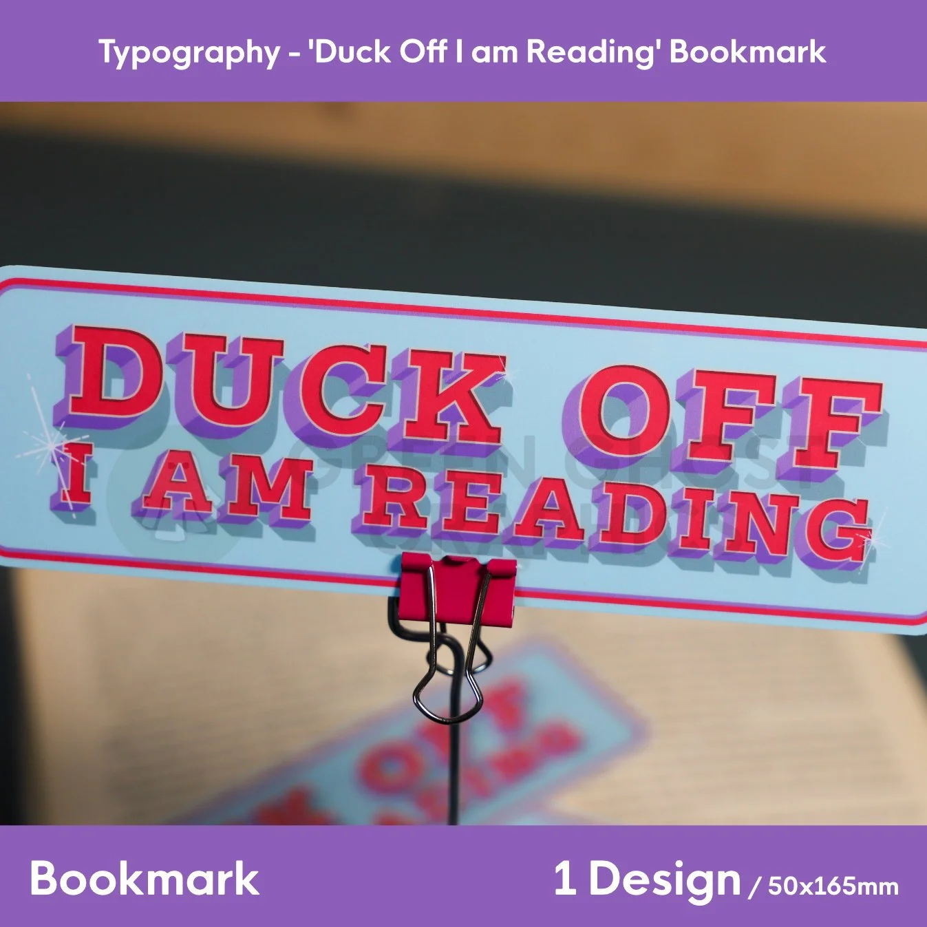 A tall blue bookmark with colourful 3D‑style “DUCK OFF I AM READING” lettering clipped to a red binder clip on a metal stand.