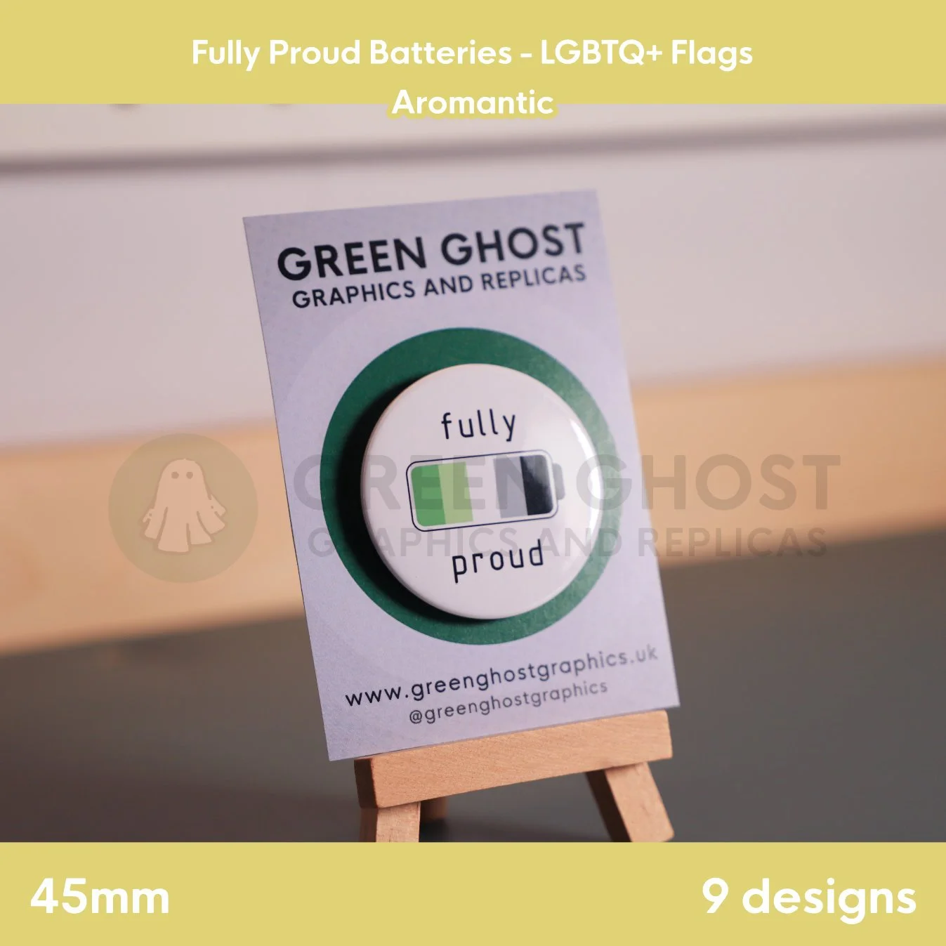 A round badge with a green, light green, white, grey, and black battery design displayed on a branded backing card on a wooden easel.