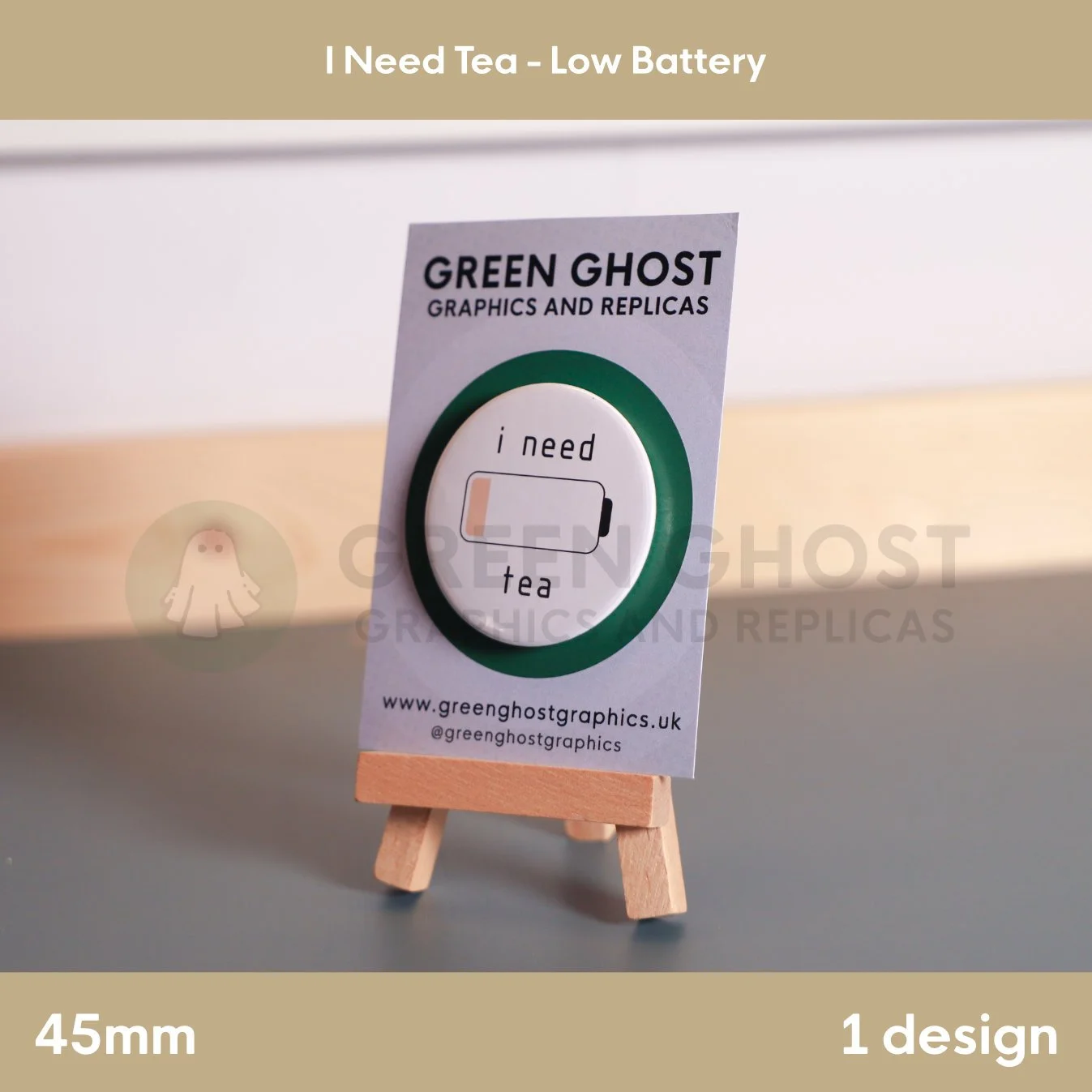A white badge with “i need tea” text beside a low‑battery icon mounted on a branded backing card.