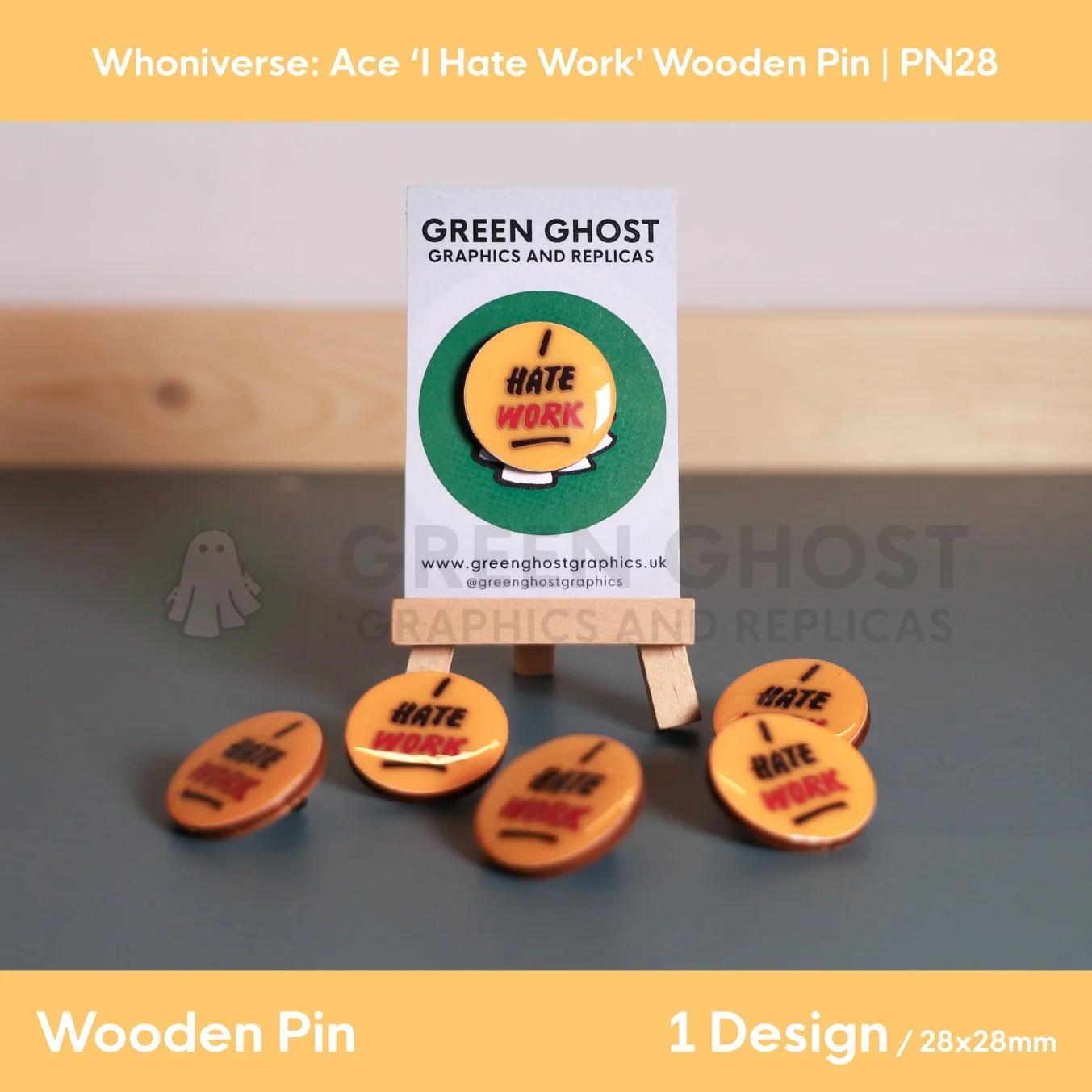 A circular wooden pin with a yellow background and a coloured text, “I HATE WORK” displayed on a branded backing card on a wooden easel with several identical pins arranged in front.