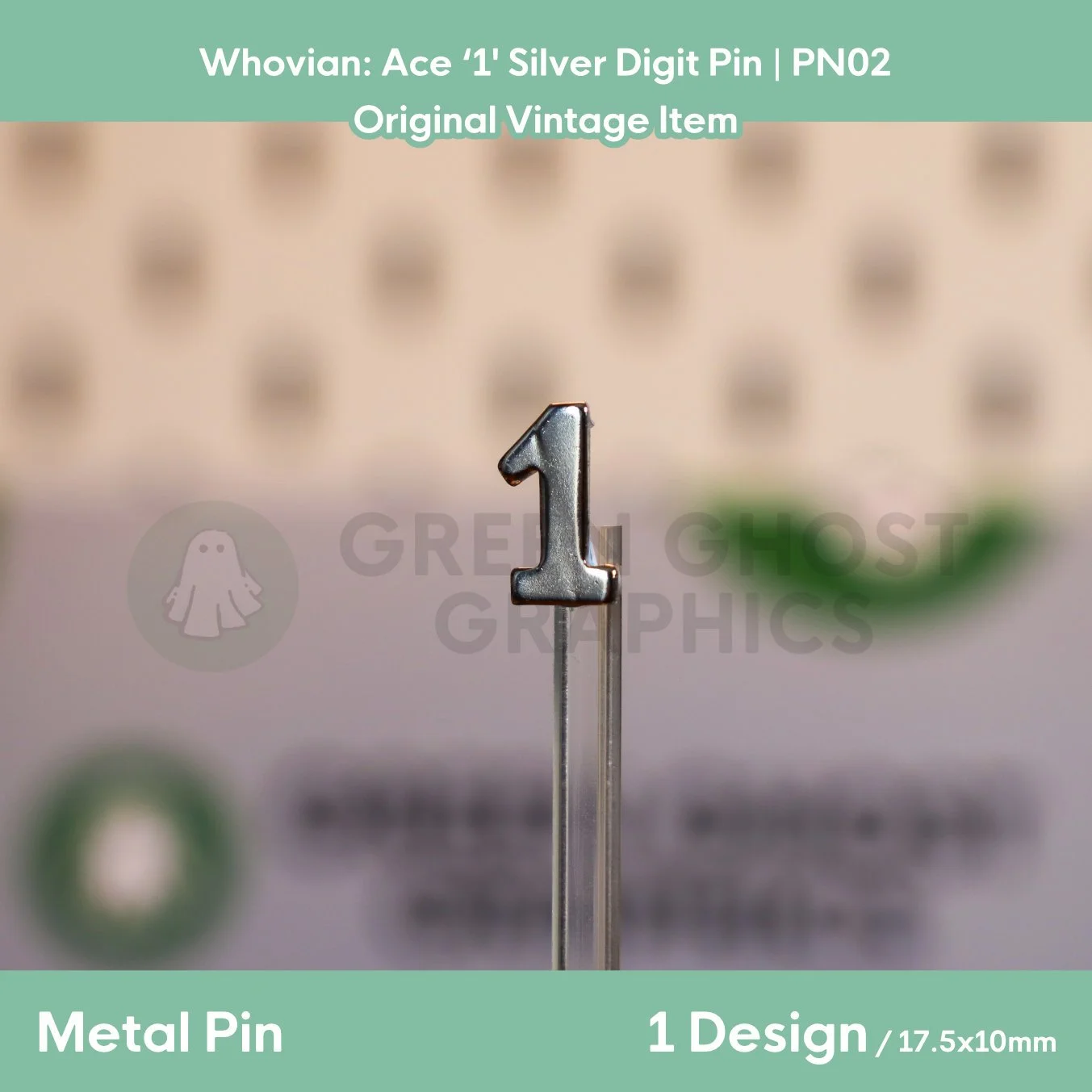 A silver metal pin shaped like the number “1” displayed upright on a clear acrylic stand.