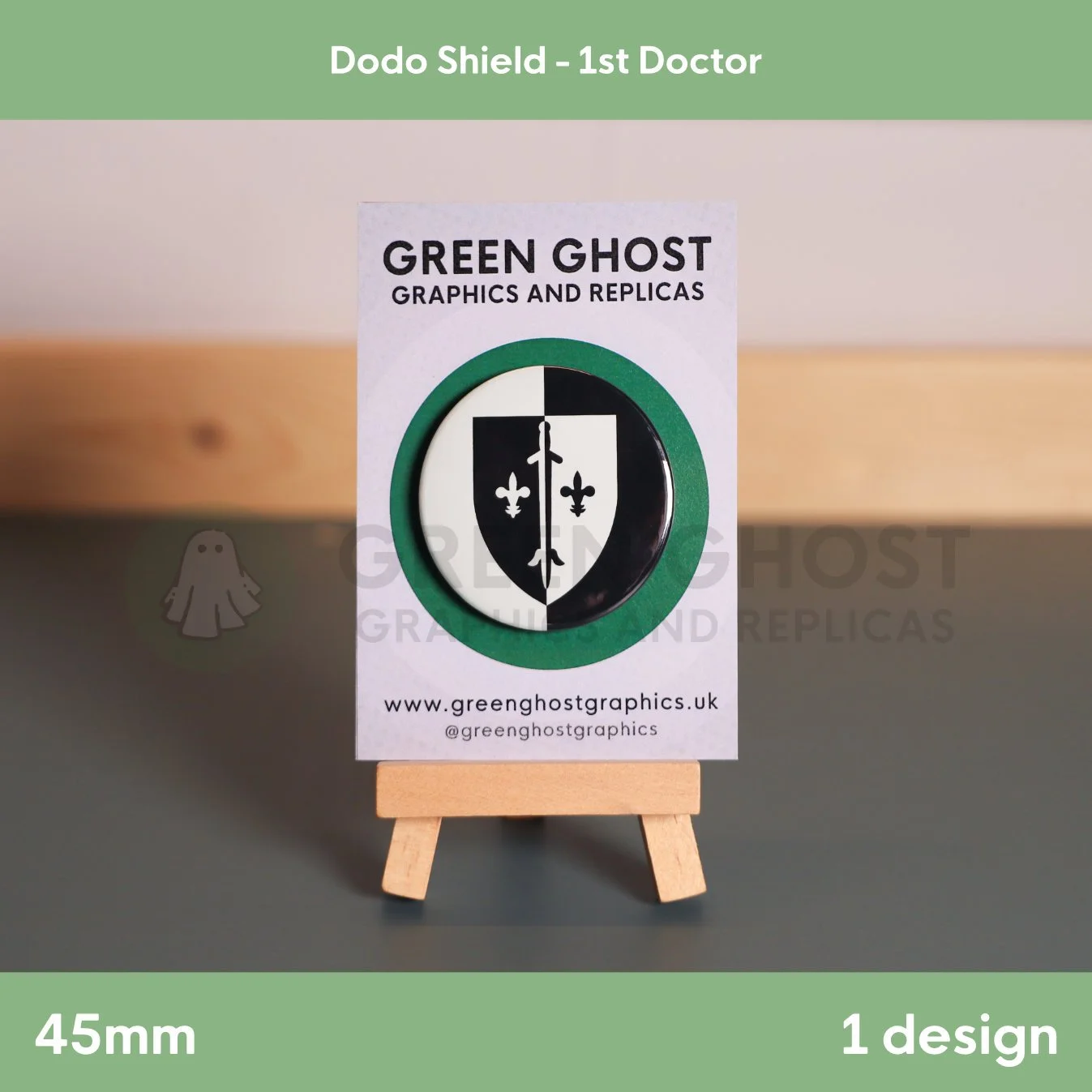 A circular badge showing a black‑and‑white heraldic shield with fleur‑de‑lis elements displayed on a wooden easel with a branded card.