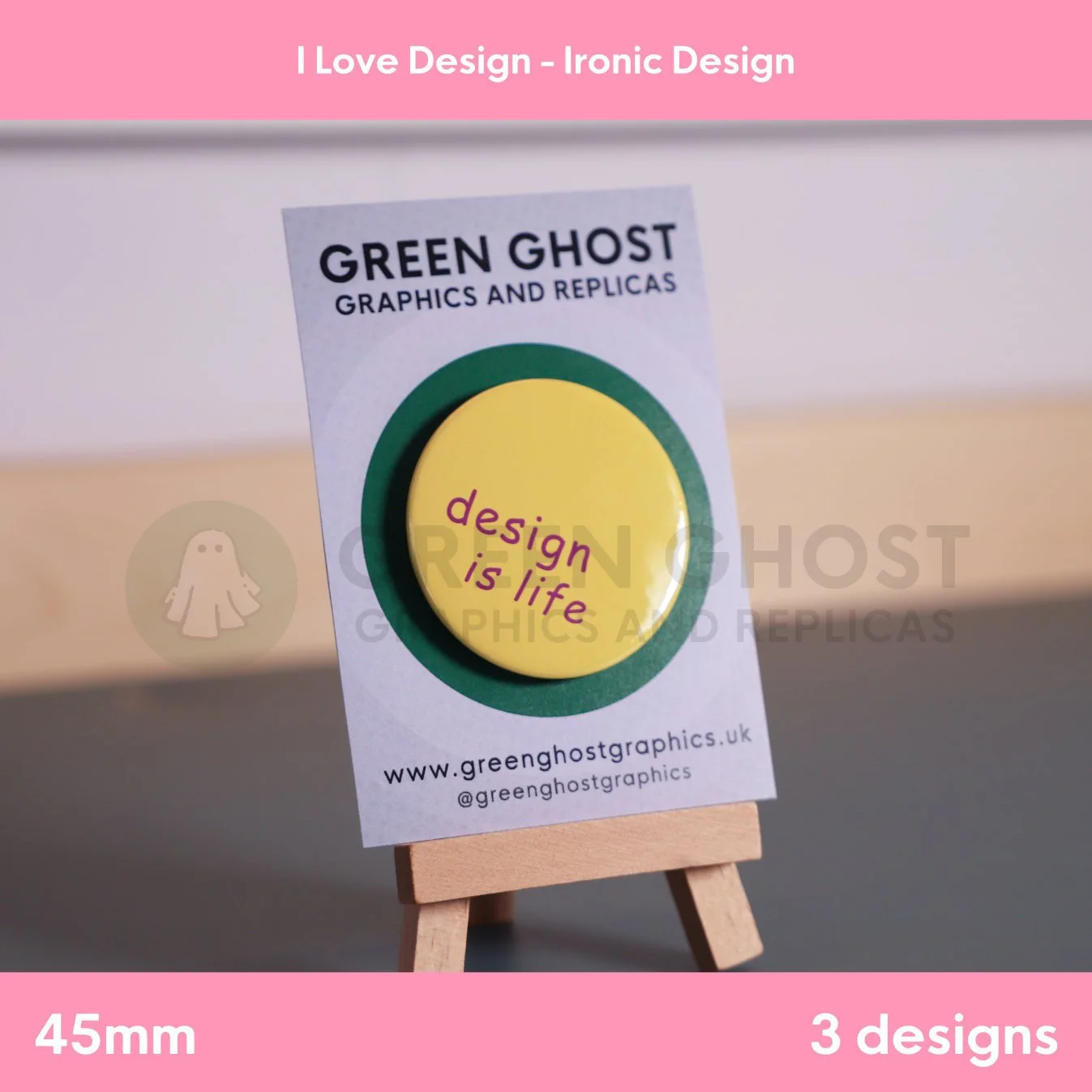 A circular yellow badge with purple “design is life” lettering displayed on a branded card on a wooden easel.