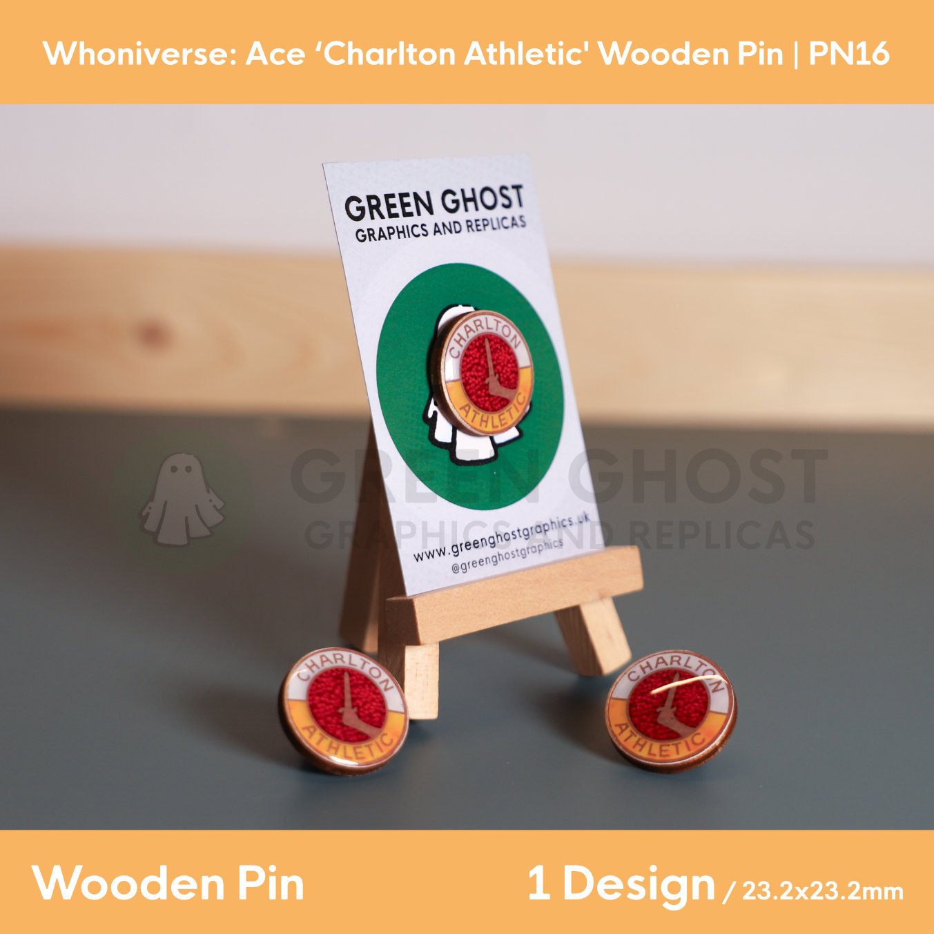 A circular wooden “Charlton Athletic” pin attached to a branded backing card on a wooden easel, with two identical pins placed in front on a flat surface.