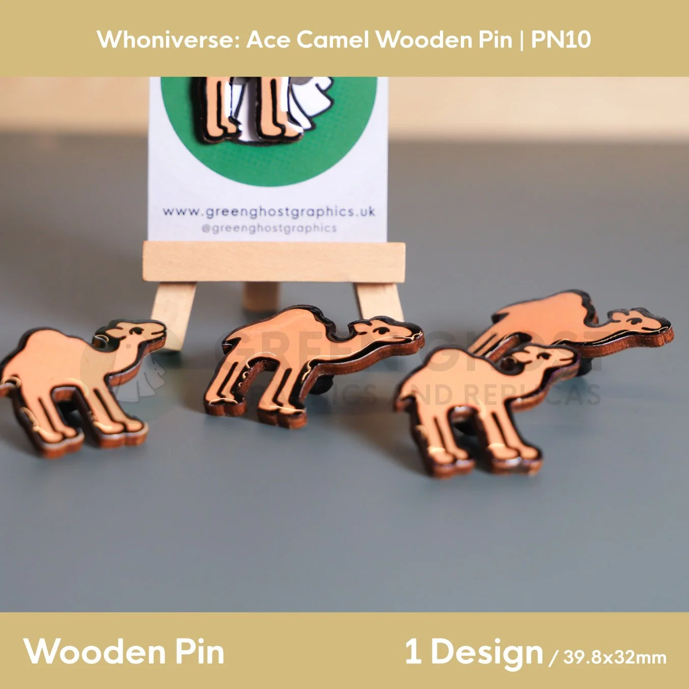 Several wooden camel‑shaped pins displayed on a flat surface, with one pin attached to a branded backing card on a small wooden easel.g